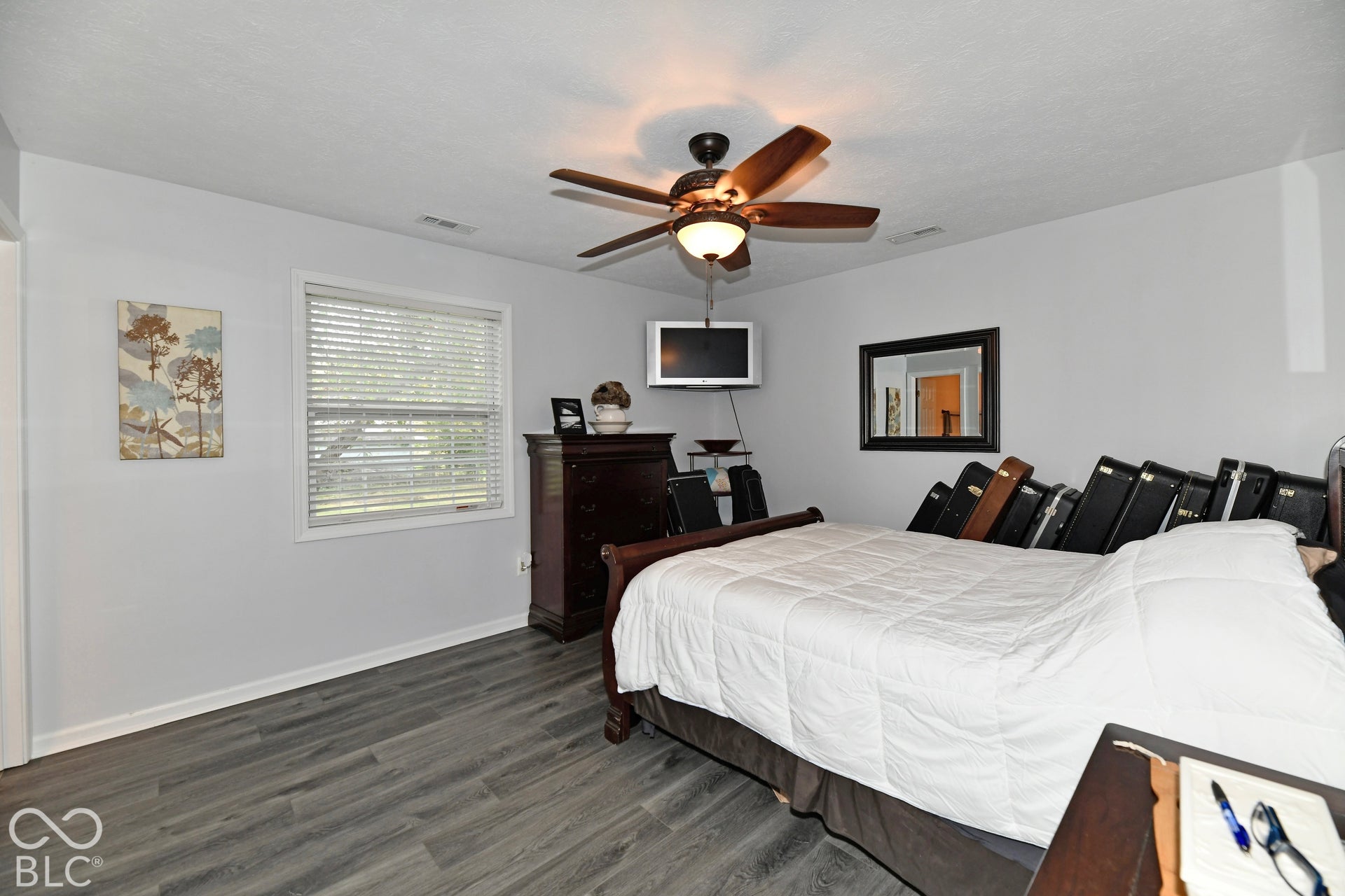 Interior space featuring wood-finish flooring, a ceiling fan with integrated light fixture, and a window with horizontal blinds