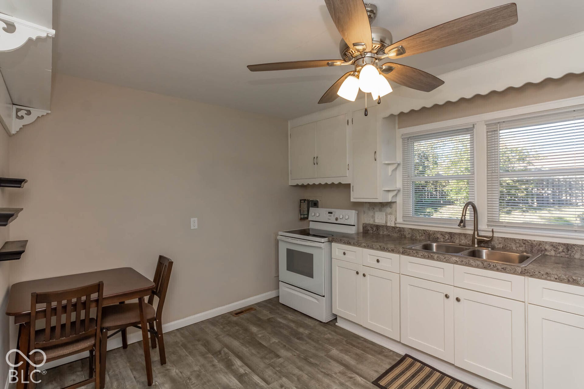 Kitchen featuring white cabinetry, wood-finish flooring, a stainless steel double-basin sink with a gooseneck faucet, and an integrated ceiling fan with light fixture