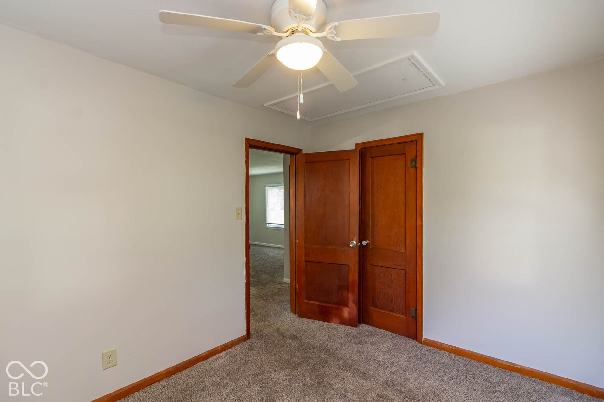 Room featuring a ceiling fan with integrated lighting, wall-to-wall carpeting, and natural-finish wood interior doors