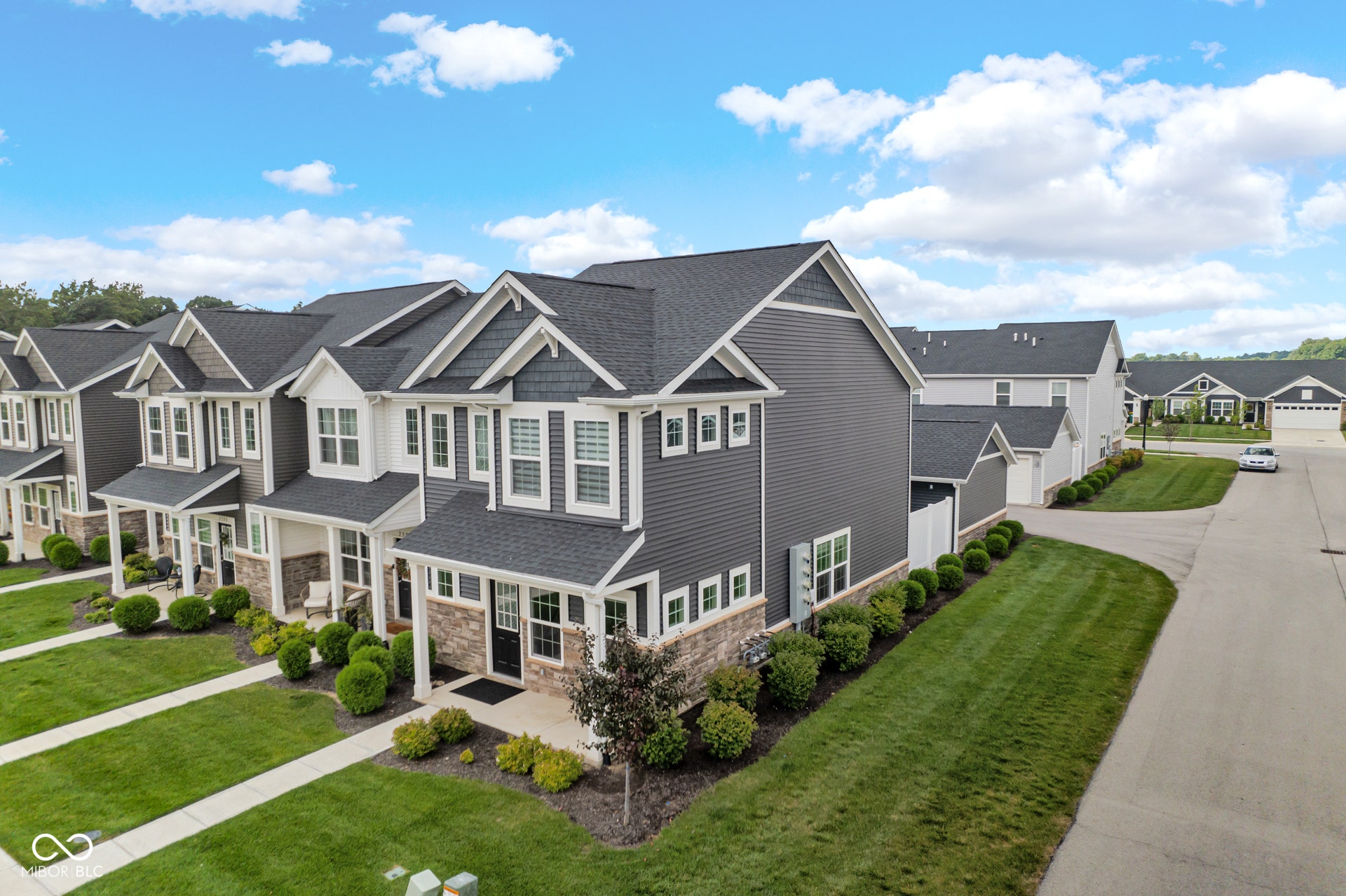 view of front of home with a residential view, concrete driveway, stone siding, a front yard, and a garage