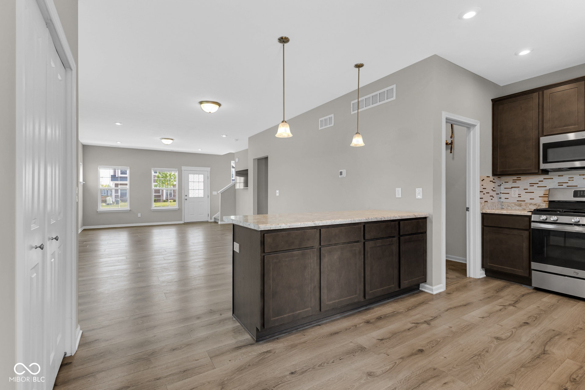 kitchen featuring appliances with stainless steel finishes, dark brown cabinets, light wood finished floors, open floor plan, and recessed lighting
