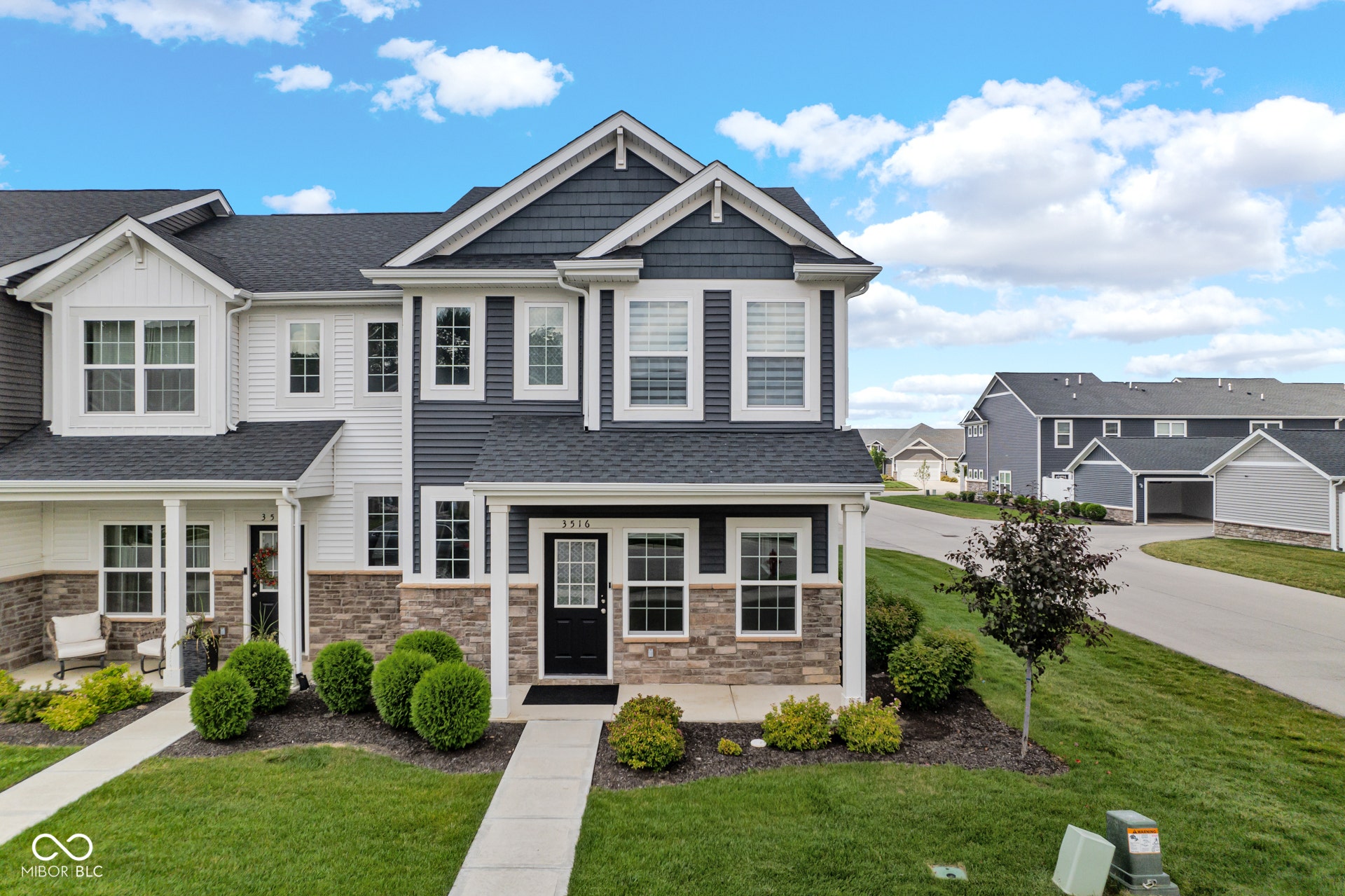 craftsman inspired home featuring covered porch, a front yard, roof with shingles, and stone siding