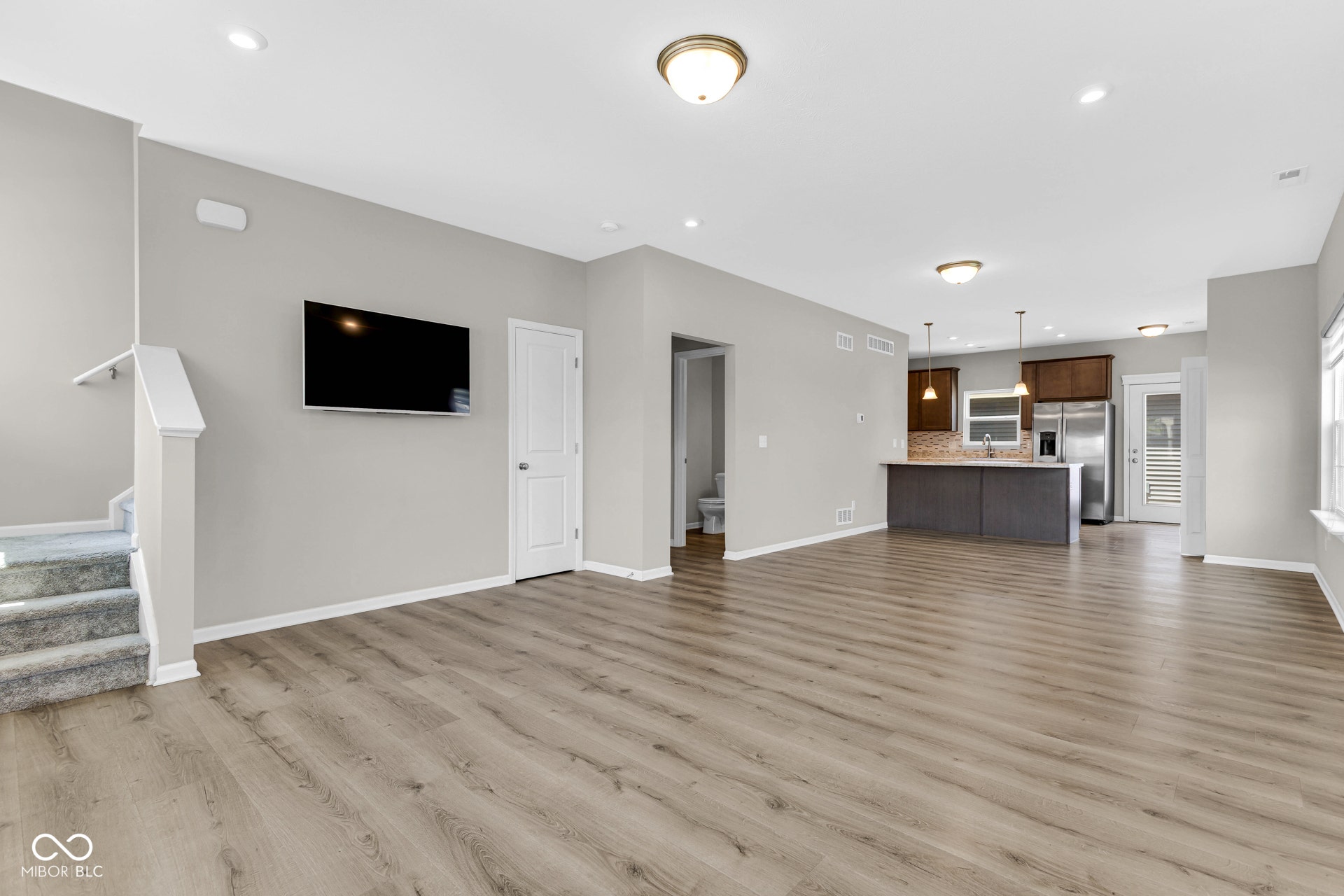 unfurnished living room featuring light wood-style floors, recessed lighting, and stairs