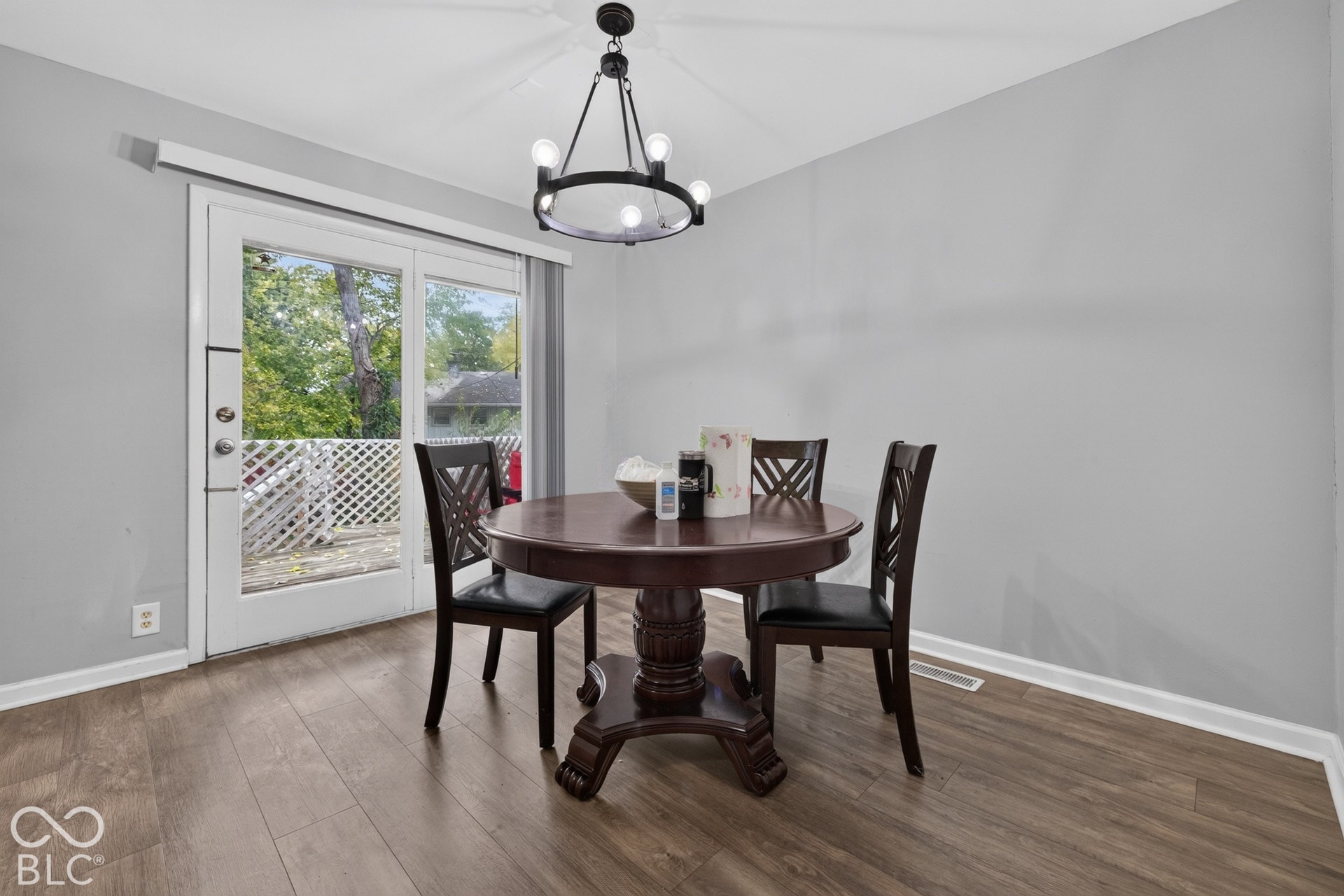 Wood-finish flooring, matte black circular chandelier, and a glass-paneled exterior door