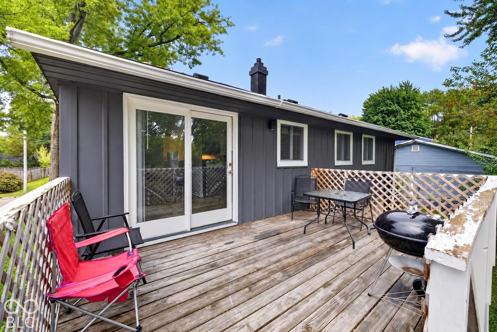 Elevated exterior deck featuring vertical siding, sliding glass doors, and white latticework railing