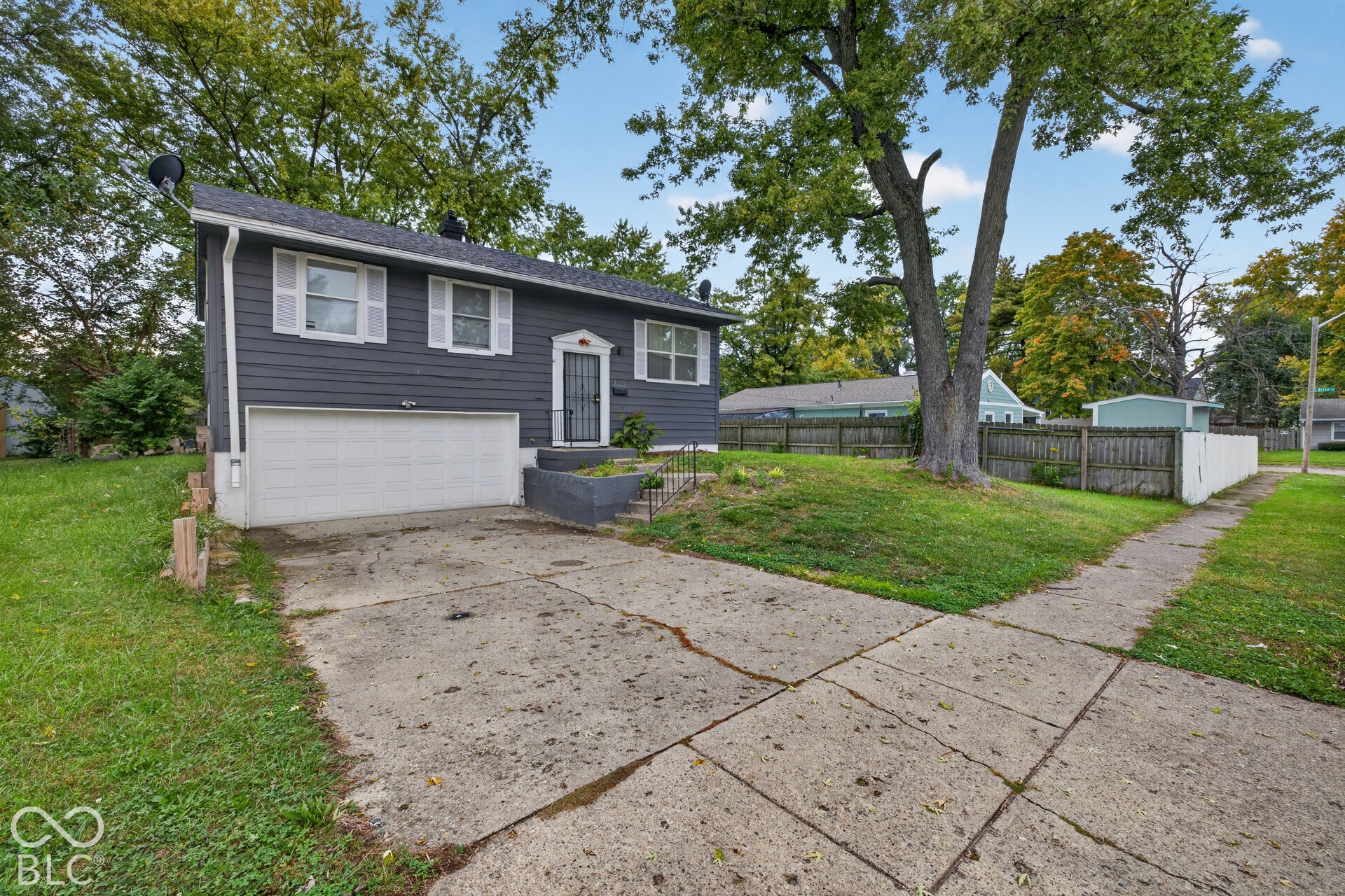 Single-story exterior with horizontal siding, attached garage, concrete driveway, and mature landscaping