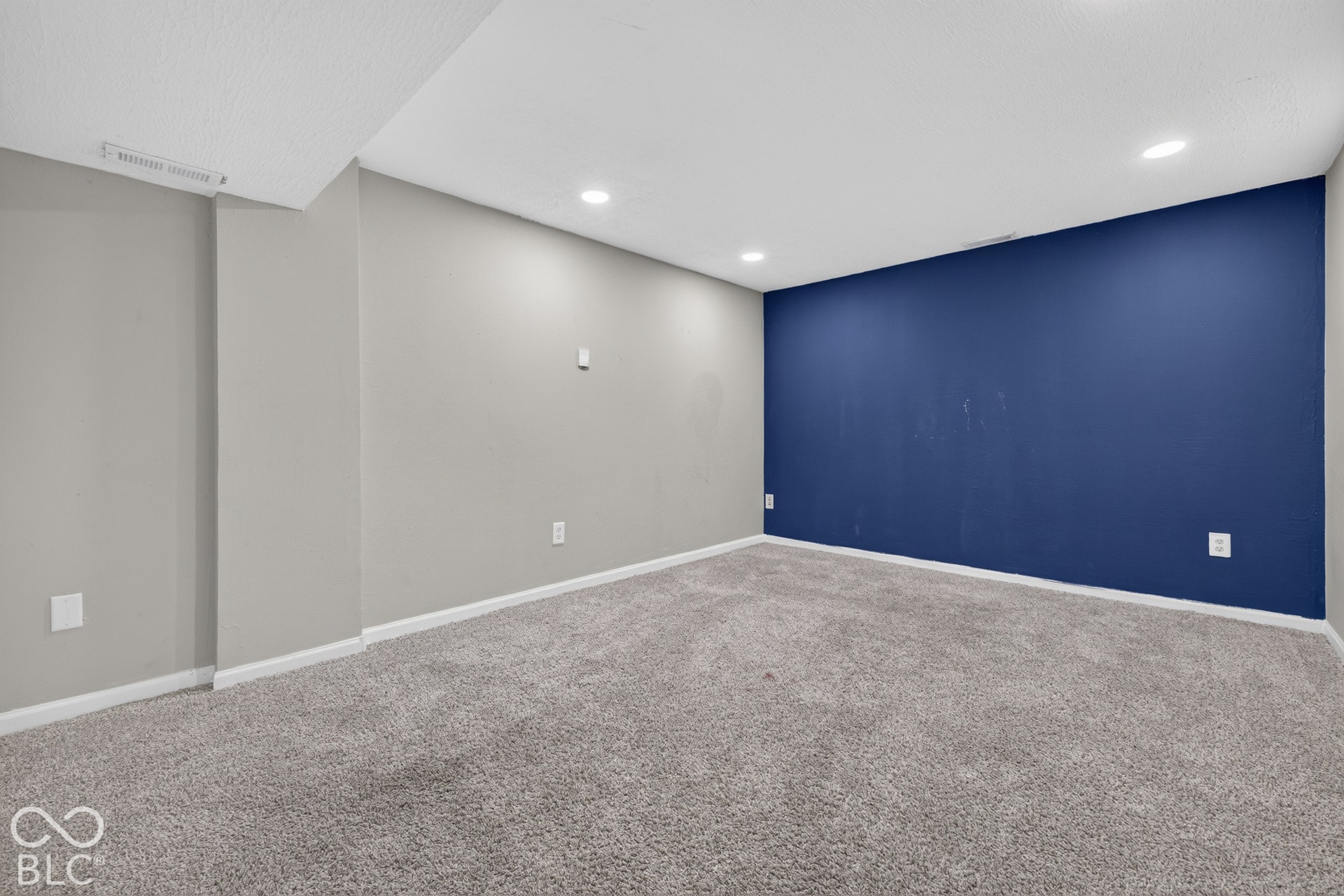 Interior space featuring neutral wall tones, a dark blue accent wall, recessed lighting, and wall-to-wall carpeting