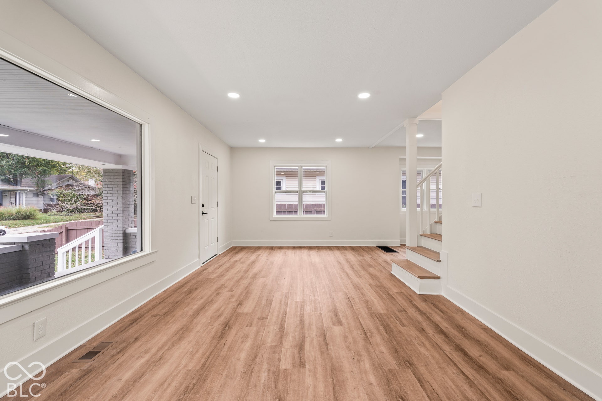 Interior space featuring wood-finish flooring, recessed lighting, expansive picture window, and stairs with wood-finish treads