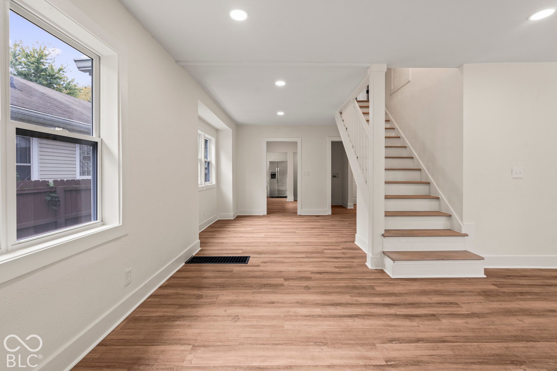 Interior space featuring wood-finish flooring, recessed lighting, white stairwell with wooden treads, and multi-pane windows