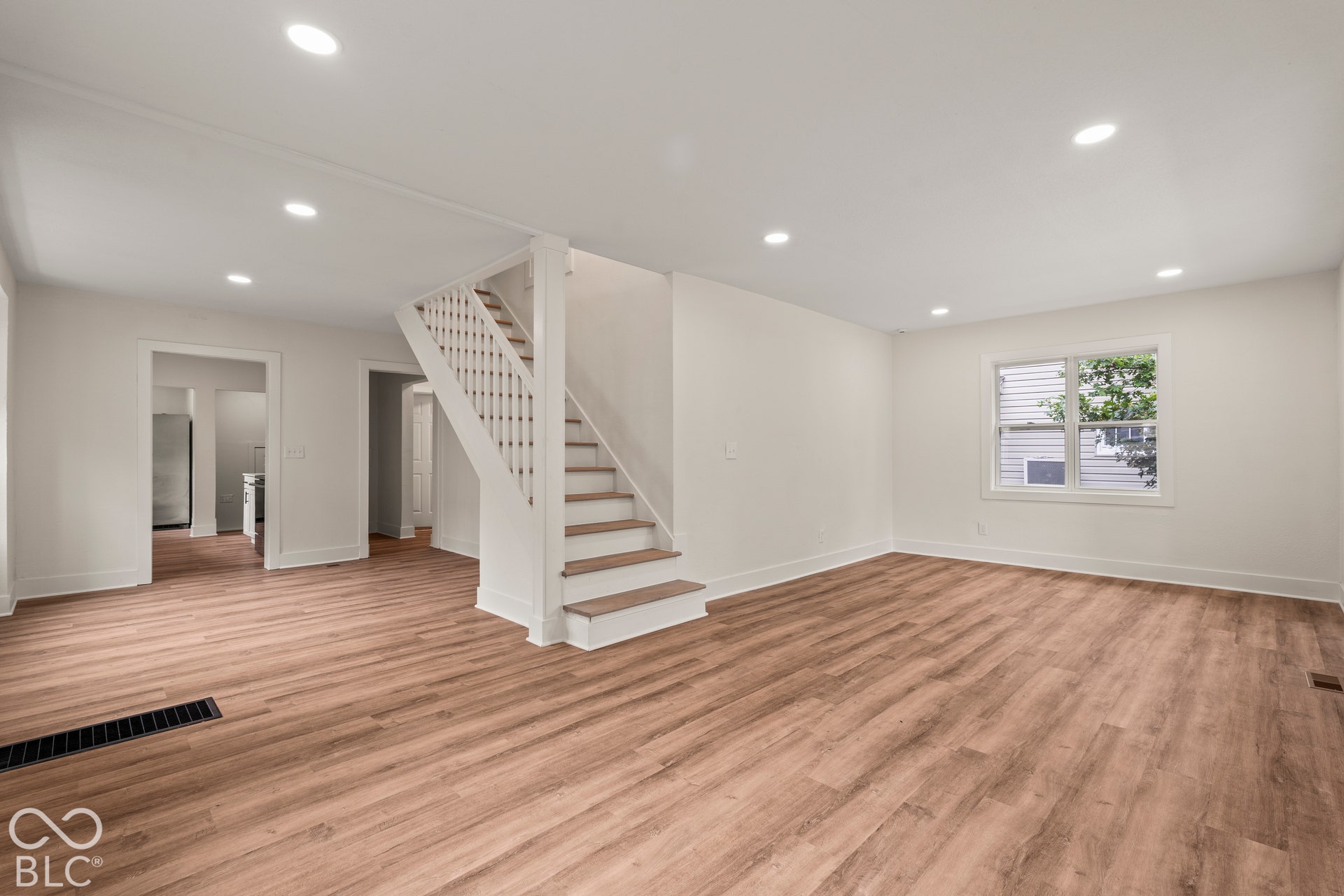 Open-concept interior featuring wood-finish flooring, recessed lighting, and a staircase with white balusters and wood-tone treads
