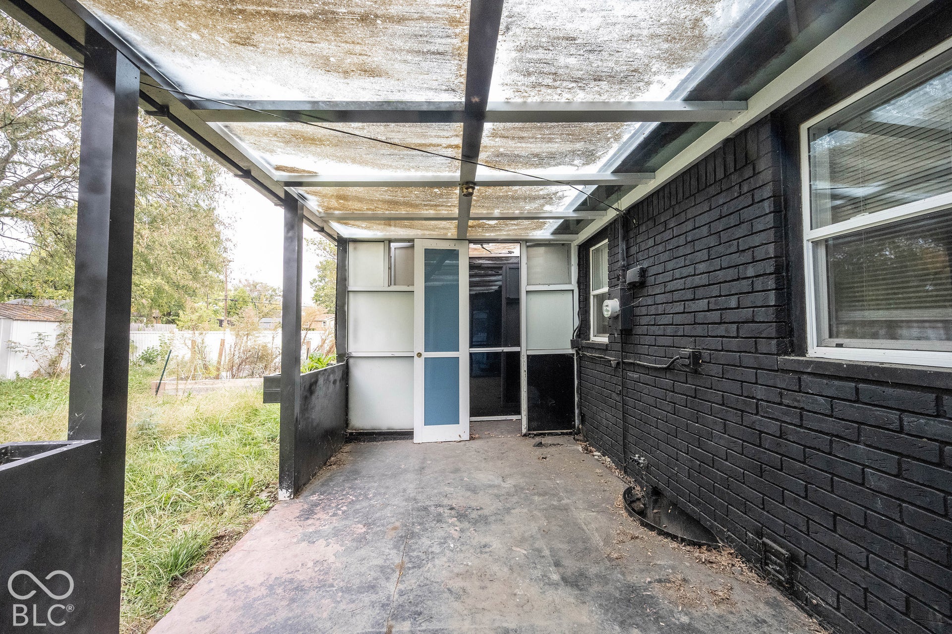 Covered patio featuring a painted brick exterior, a concrete floor, and a translucent roof structure