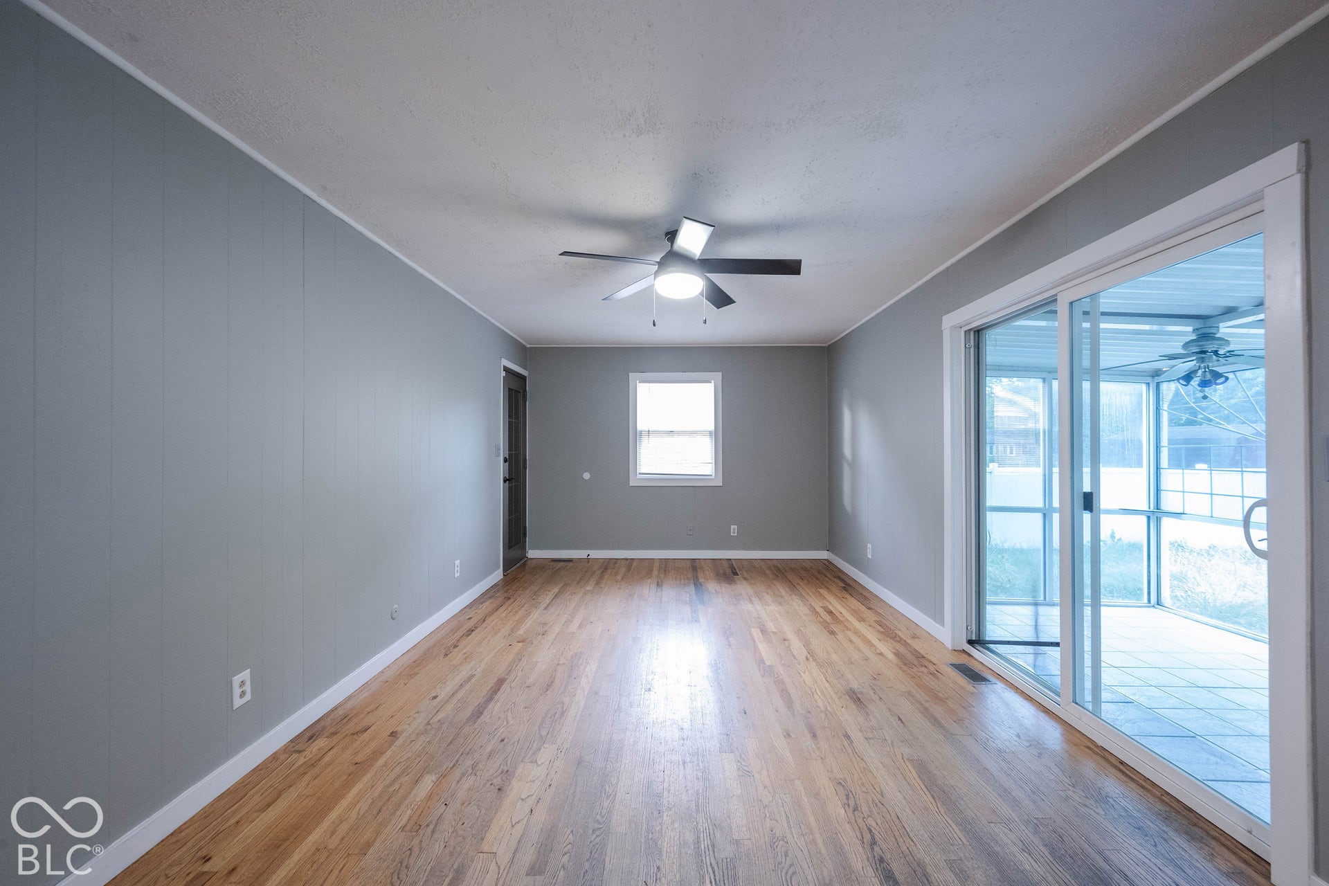 Interior space featuring wood-finish flooring, sliding glass doors, a ceiling fan with integrated lighting, and a window providing natural light