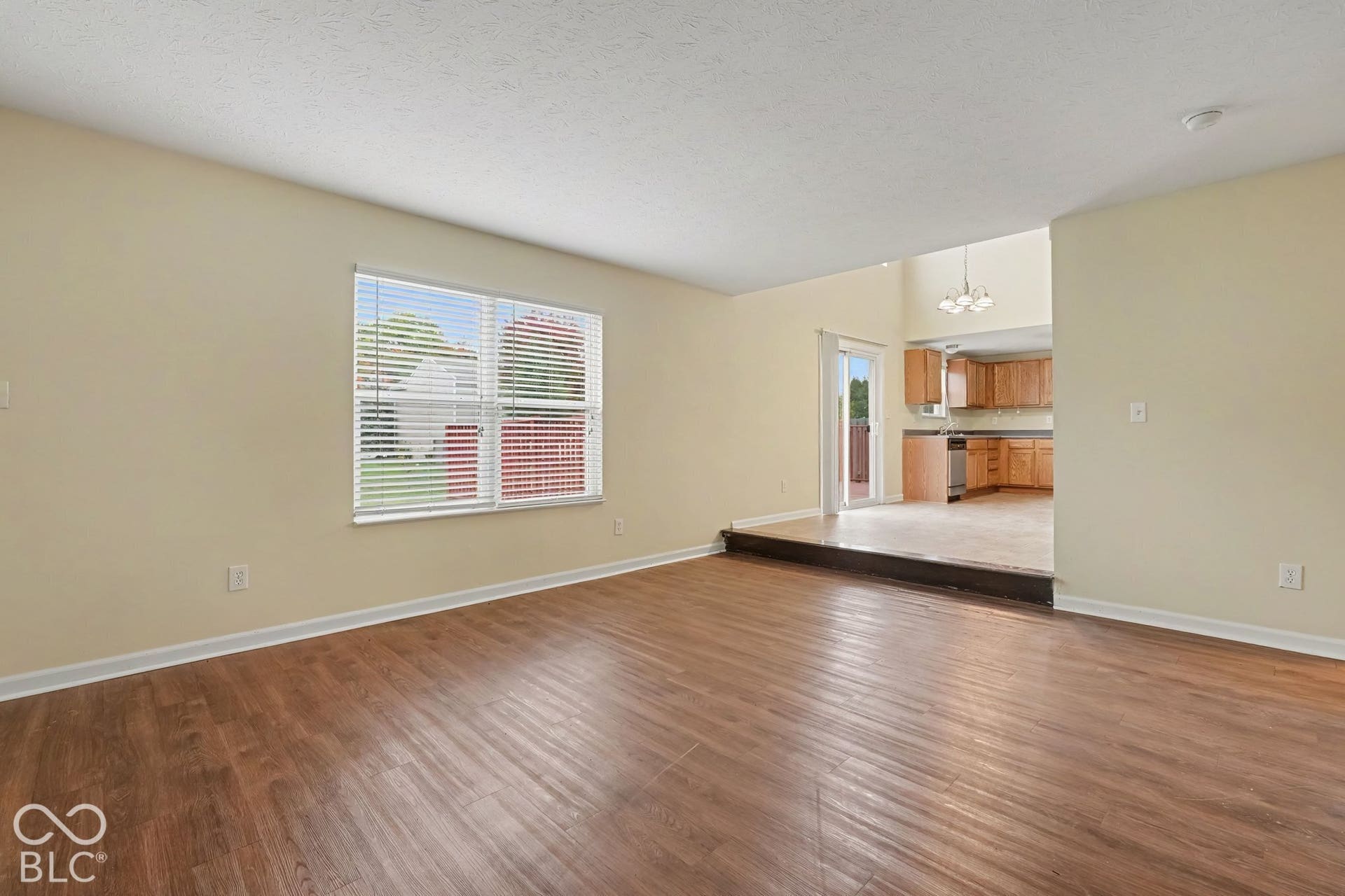 Living area featuring wood-finish flooring, a multi-pane window, split-level architectural detail, and sliding glass doors