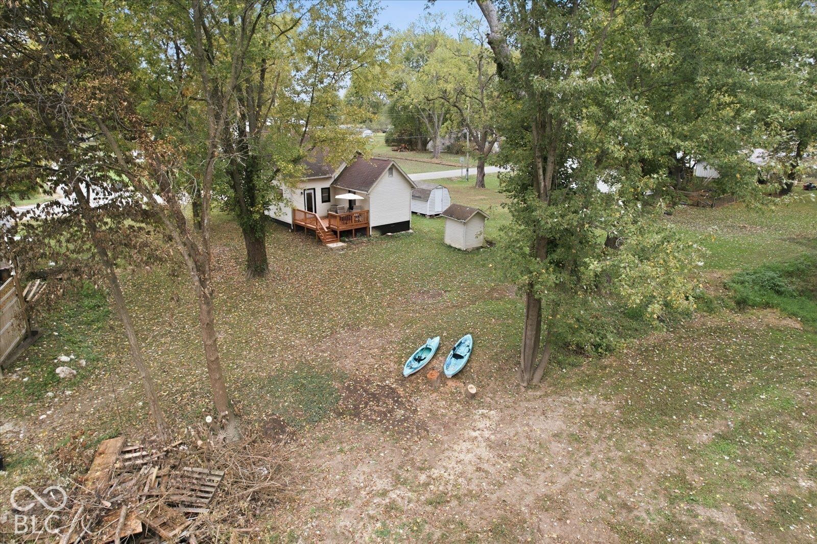 Expansive lot featuring mature trees, a wood deck, and detached outbuildings
