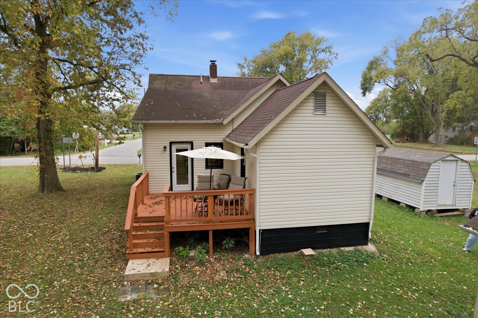 Exterior siding with a shingled roof, elevated wood deck, and detached storage structure situated on a grass lot
