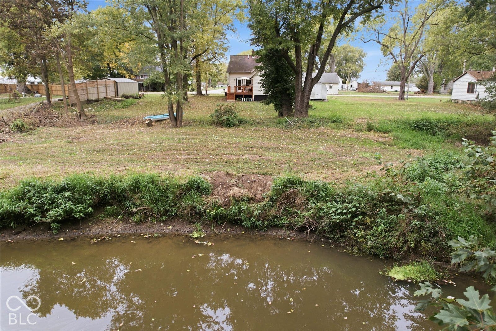 Expansive lot featuring water frontage, mature trees, and a wooden deck