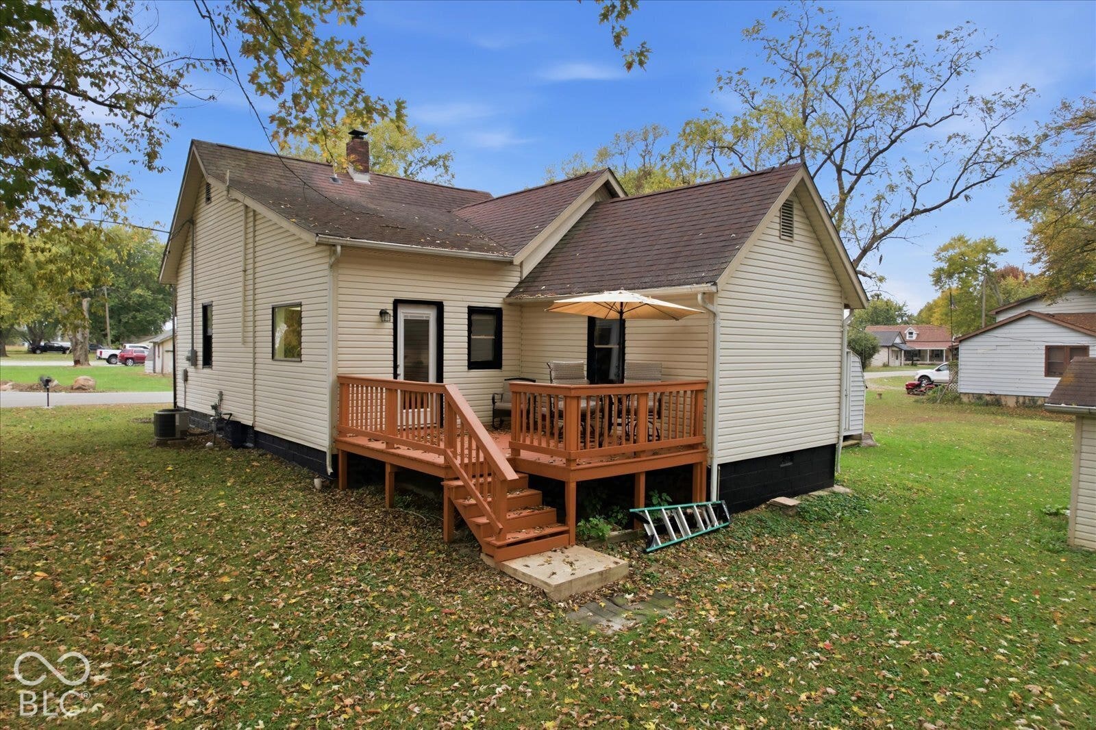 Exterior featuring light-colored siding, a dark roof with a chimney, and an elevated wood deck with stairs