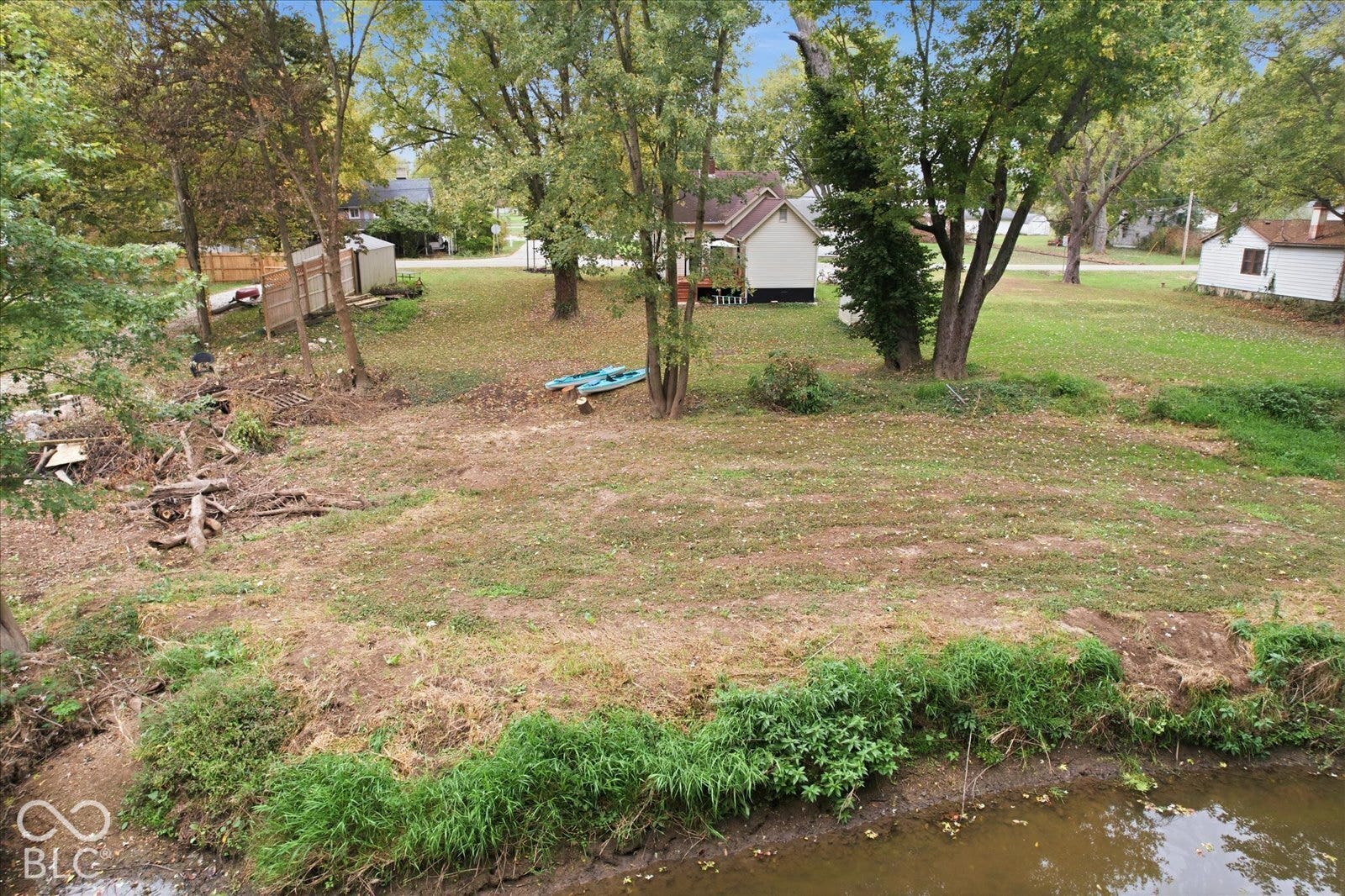 Expansive backyard featuring mature trees, natural water frontage, and open lawn space