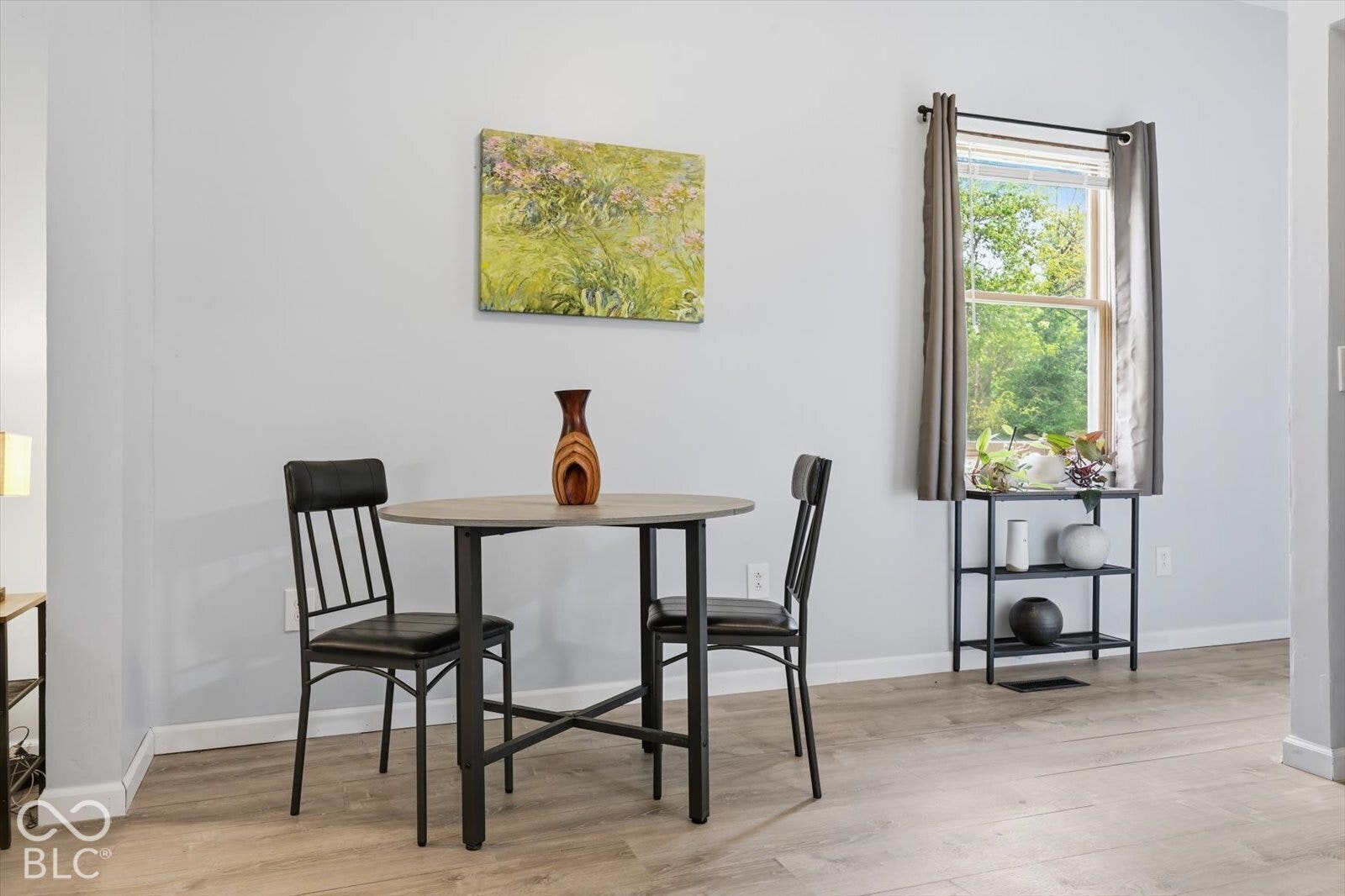 Neutral-toned interior featuring wood-finish flooring and a single-pane window with a black metal curtain rod