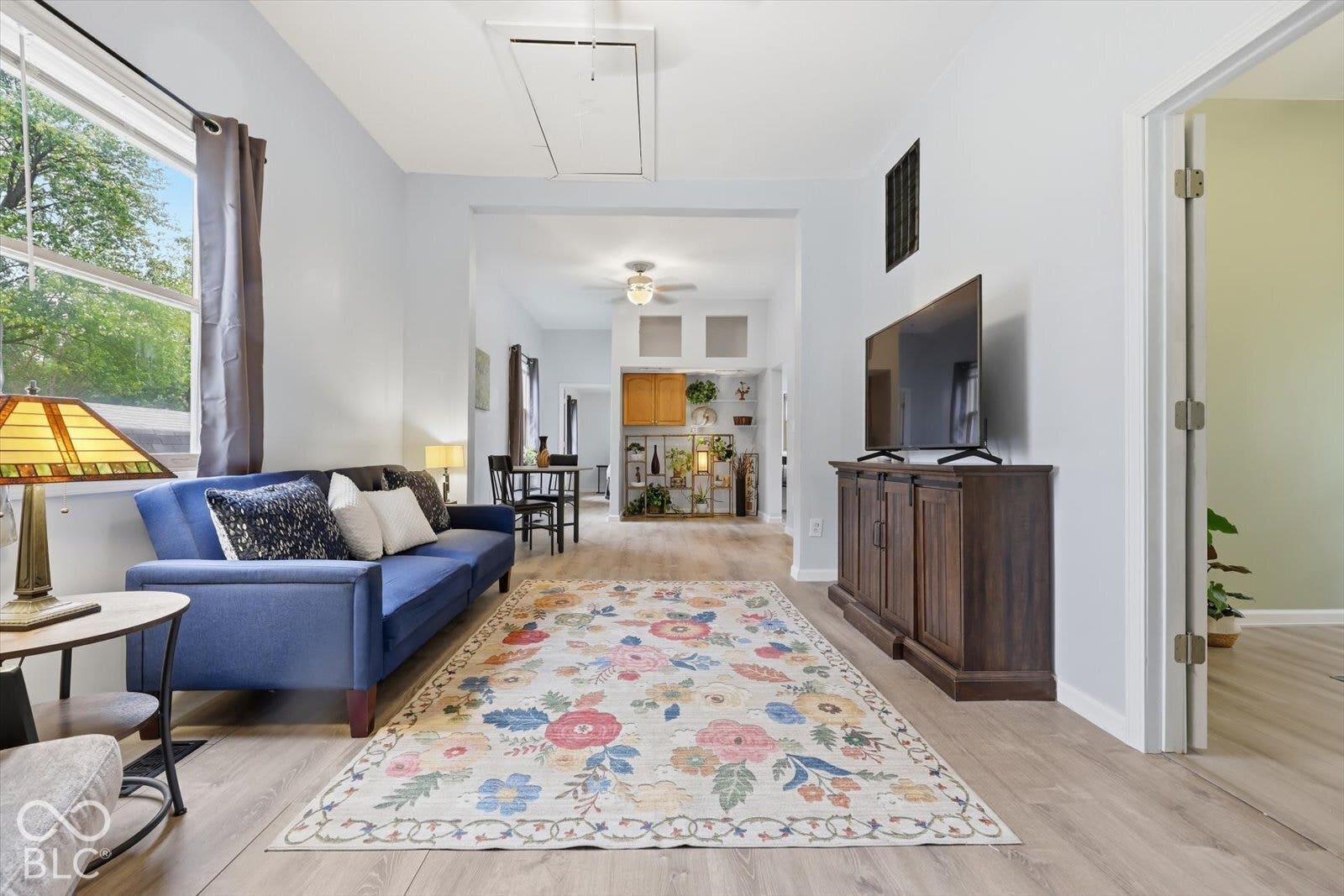 Light-toned wood-finish flooring, ceiling fan with integrated lighting, natural light through double-pane window, and recessed built-in shelving