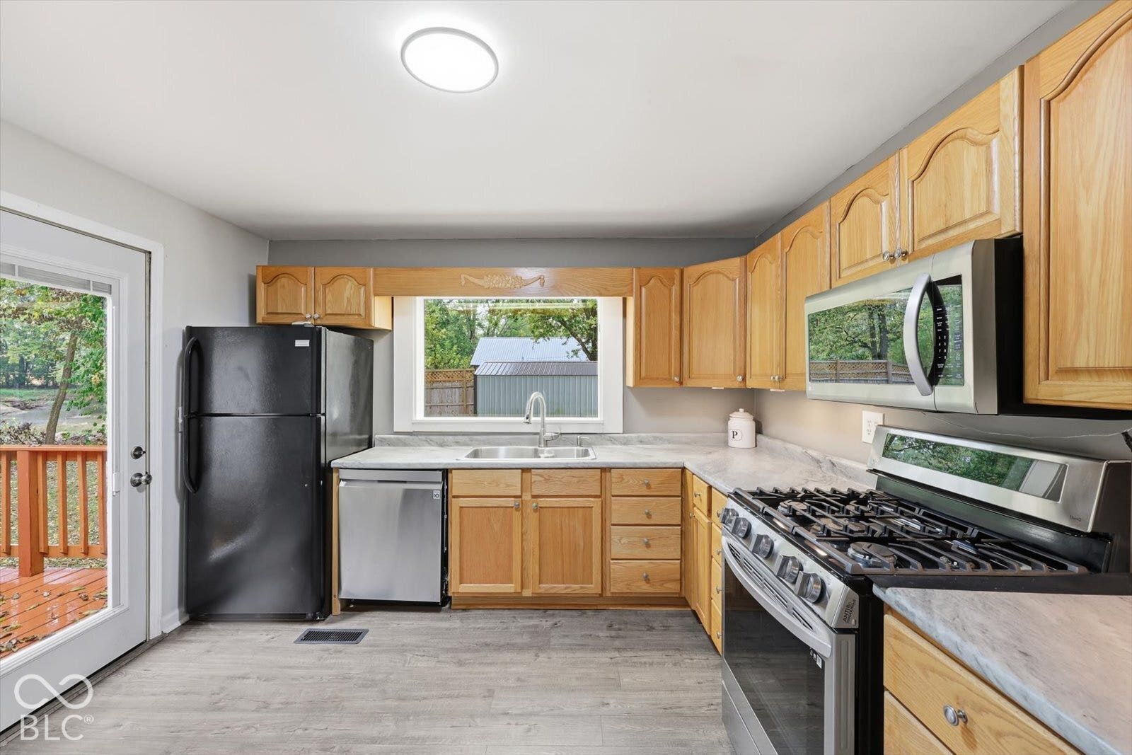 Kitchen featuring wood cabinetry, stainless steel appliances, neutral countertops, and wood-finish flooring
