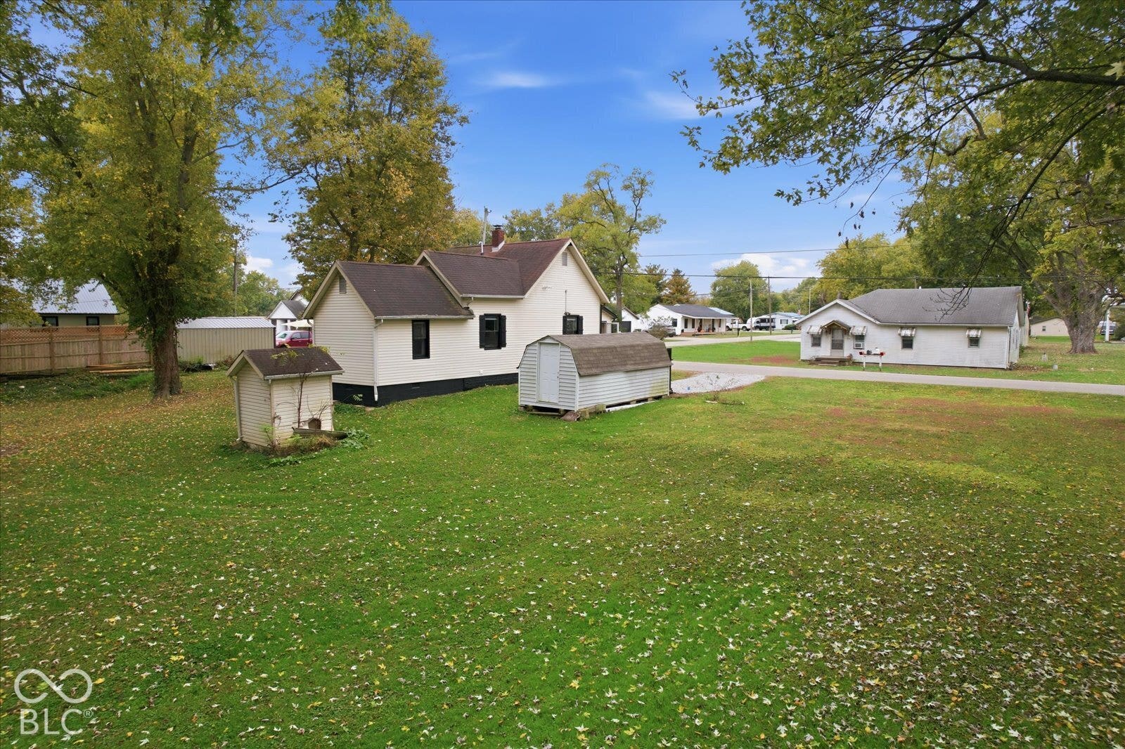 Expansive lot featuring mature trees, a detached storage structure, and wood fencing