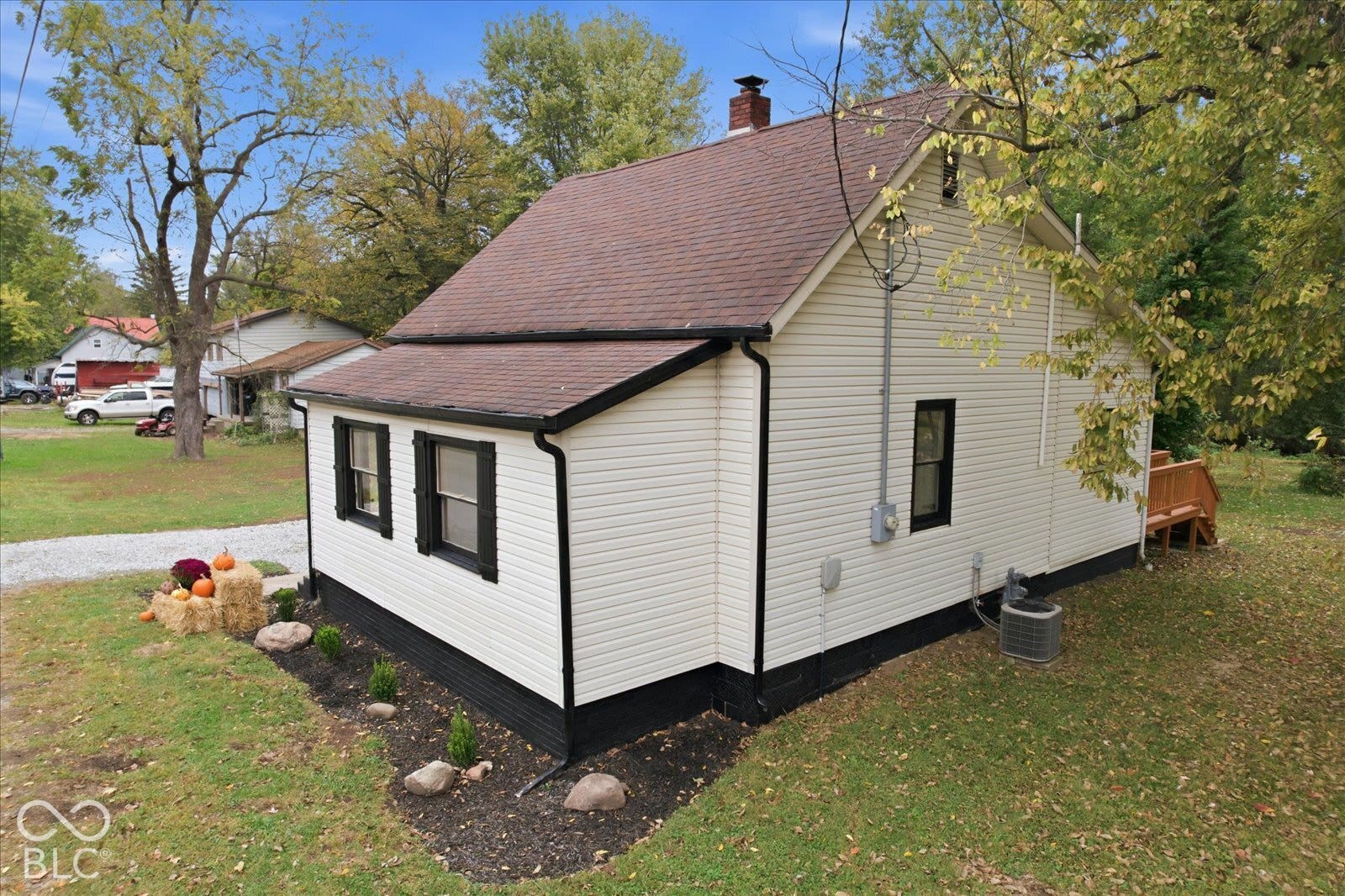 Exterior profile featuring light-colored horizontal siding, dark-toned trim, a gable roof with a masonry chimney, and a wooden deck
