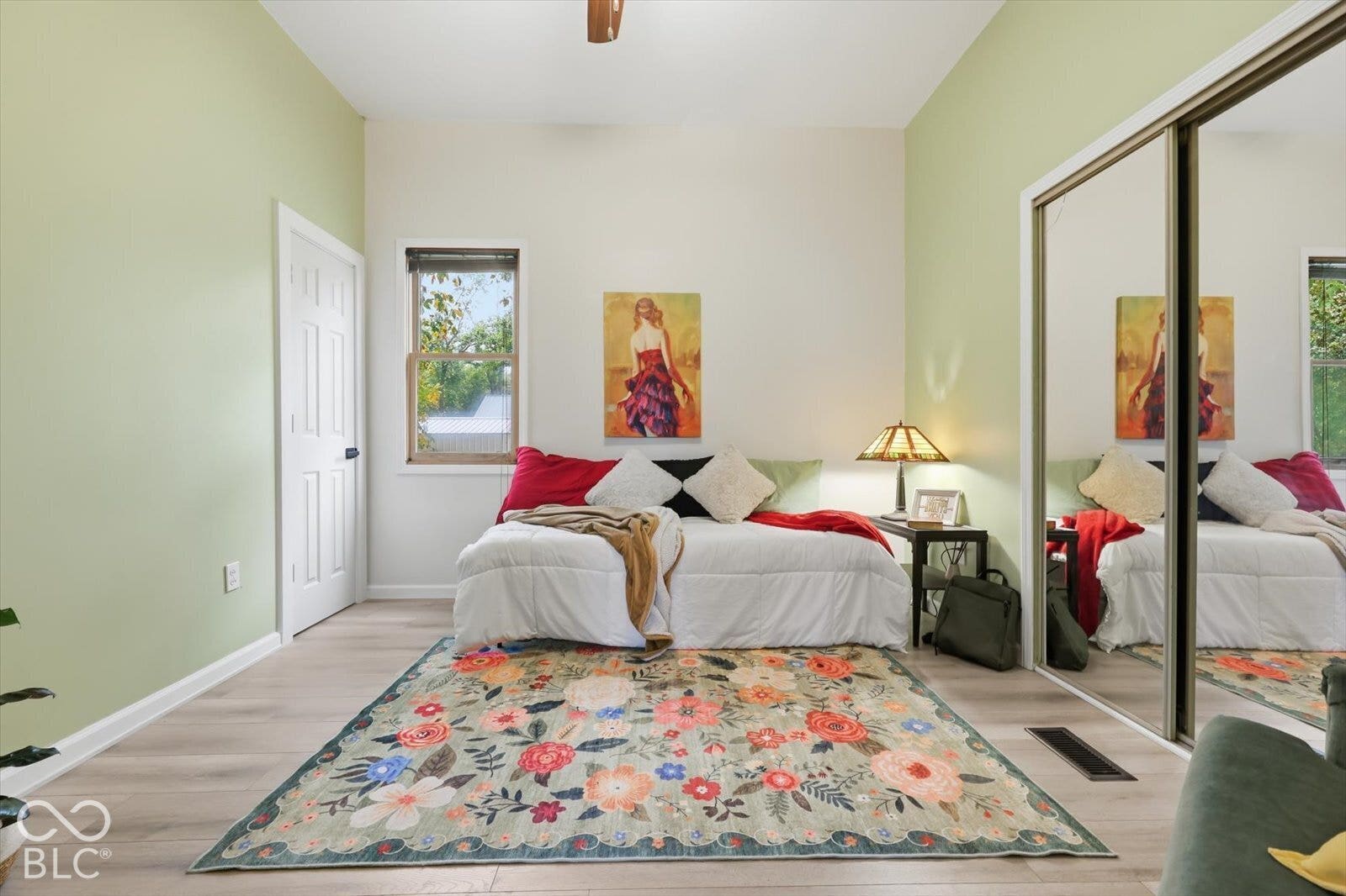 Room featuring wood-finish flooring, ceiling fan, and sliding mirrored closet doors