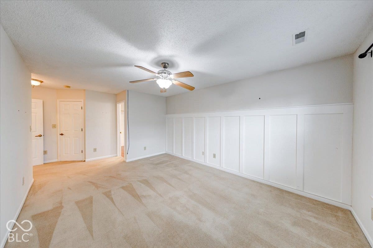 6405 Lonestar Drive, Indianapolis, IN 46237 Interior space featuring white board-and-batten wainscoting, neutral carpeting, and a multi-blade ceiling fan with integrated lighting