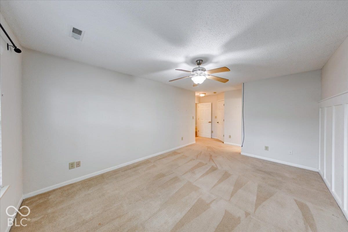 6405 Lonestar Drive, Indianapolis, IN 46237 Neutral-toned interior featuring wall-to-wall carpeting, white board and batten wainscoting, and a central ceiling fan with integrated lighting