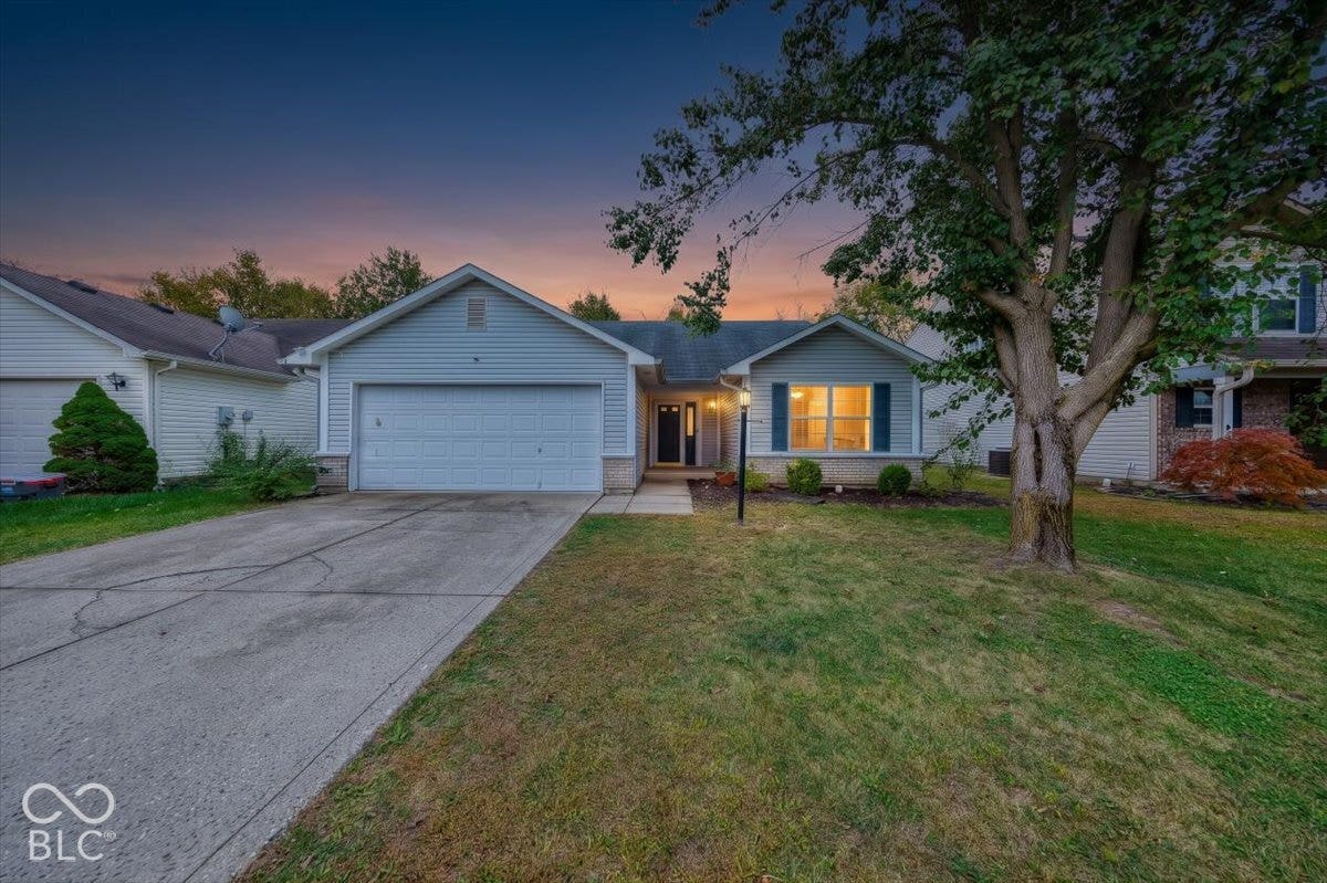 6405 Lonestar Drive, Indianapolis, IN 46237 Single-story exterior featuring horizontal siding, brick masonry detailing, an attached two-car garage, concrete driveway, and mature landscaping