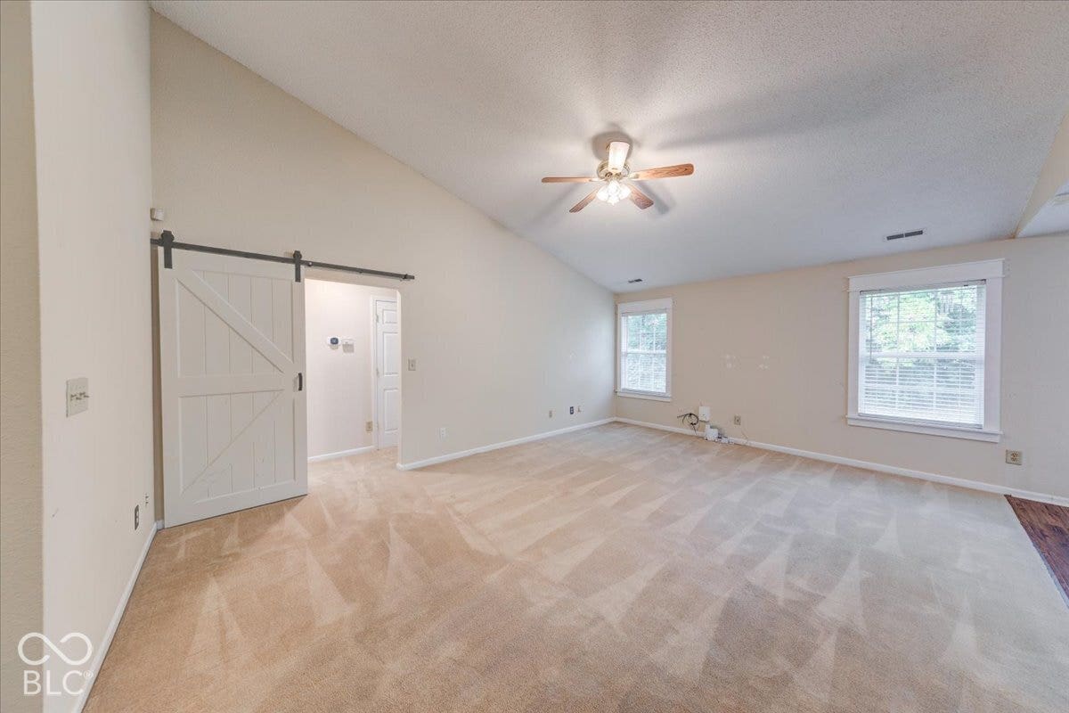 6405 Lonestar Drive, Indianapolis, IN 46237 Vaulted ceilings, sliding barn-style door, ceiling fan with integrated lighting, and multiple windows