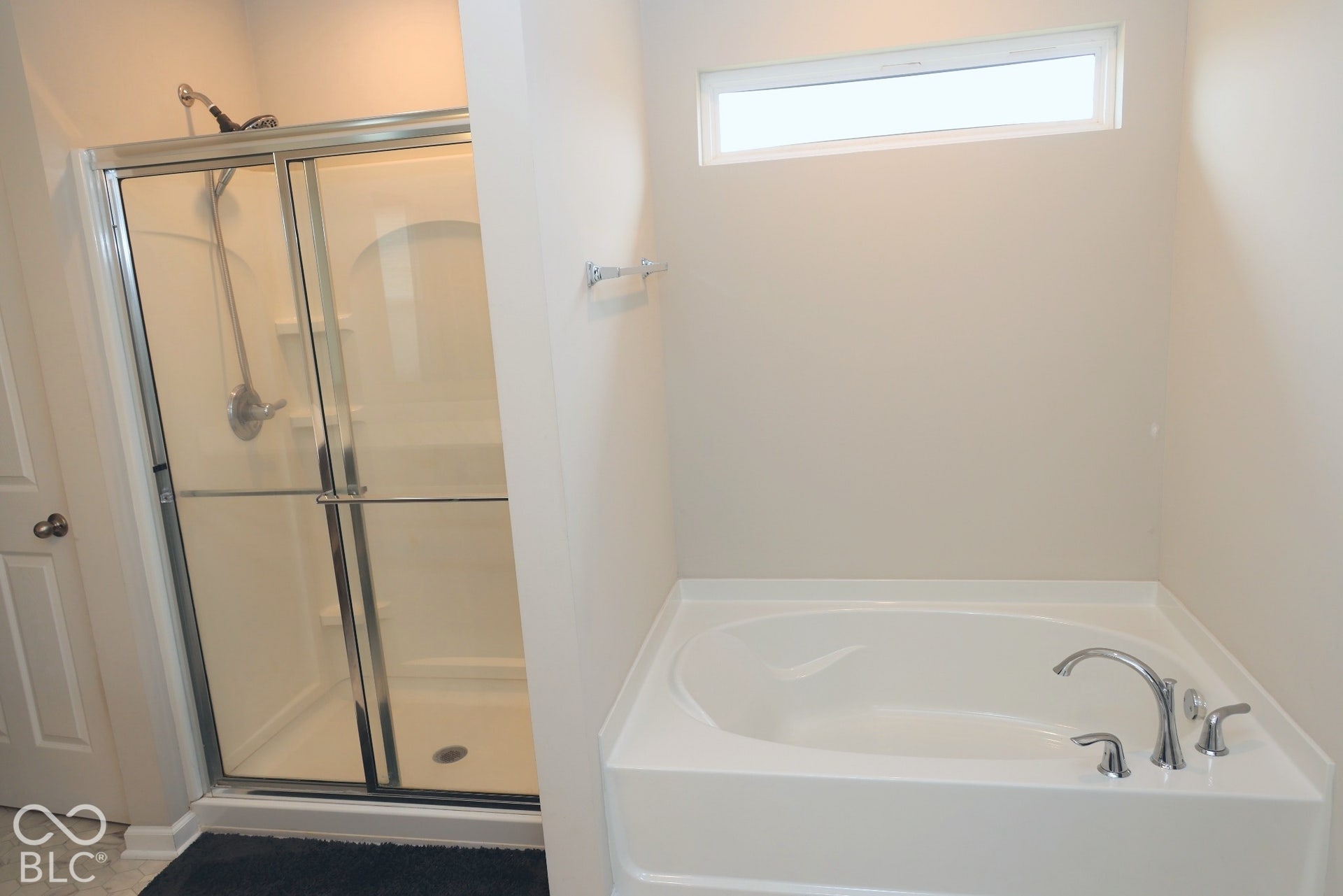 Walk-in shower with glass enclosure and chrome hardware, deep soaking tub, polished chrome tub faucet, and horizontal transom window