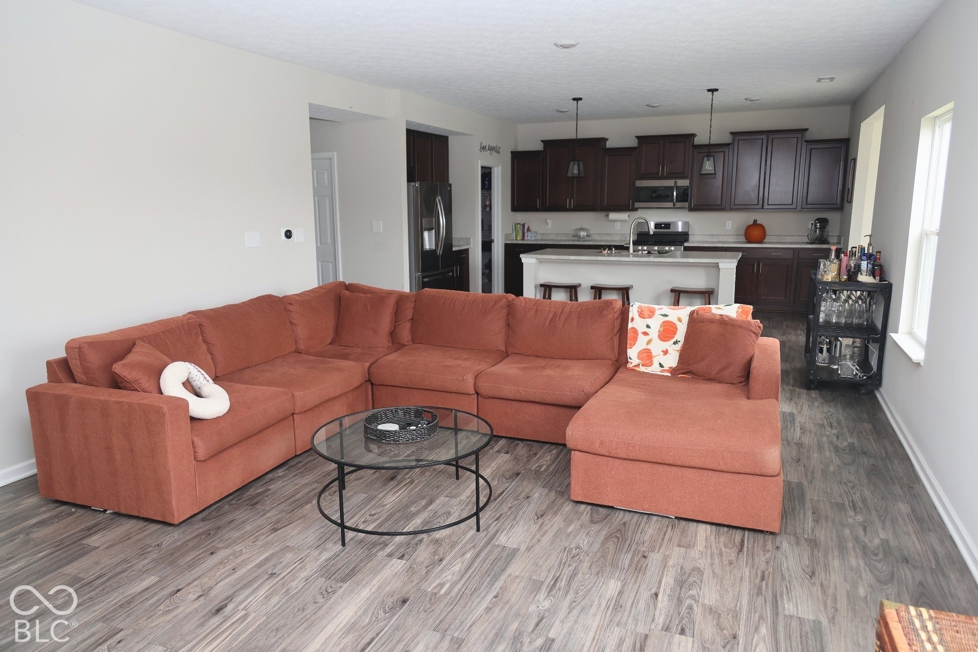 Open-concept interior featuring wood-finish flooring, dark-toned cabinetry, a center island with a stone-style countertop, and pendant lighting