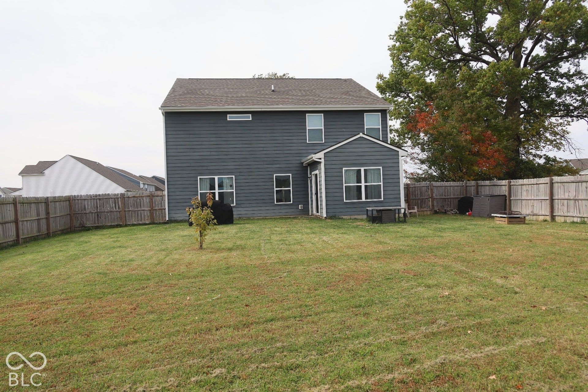 Rear exterior featuring horizontal lap siding, a shingled roof, multi-pane windows, and a fenced-in backyard