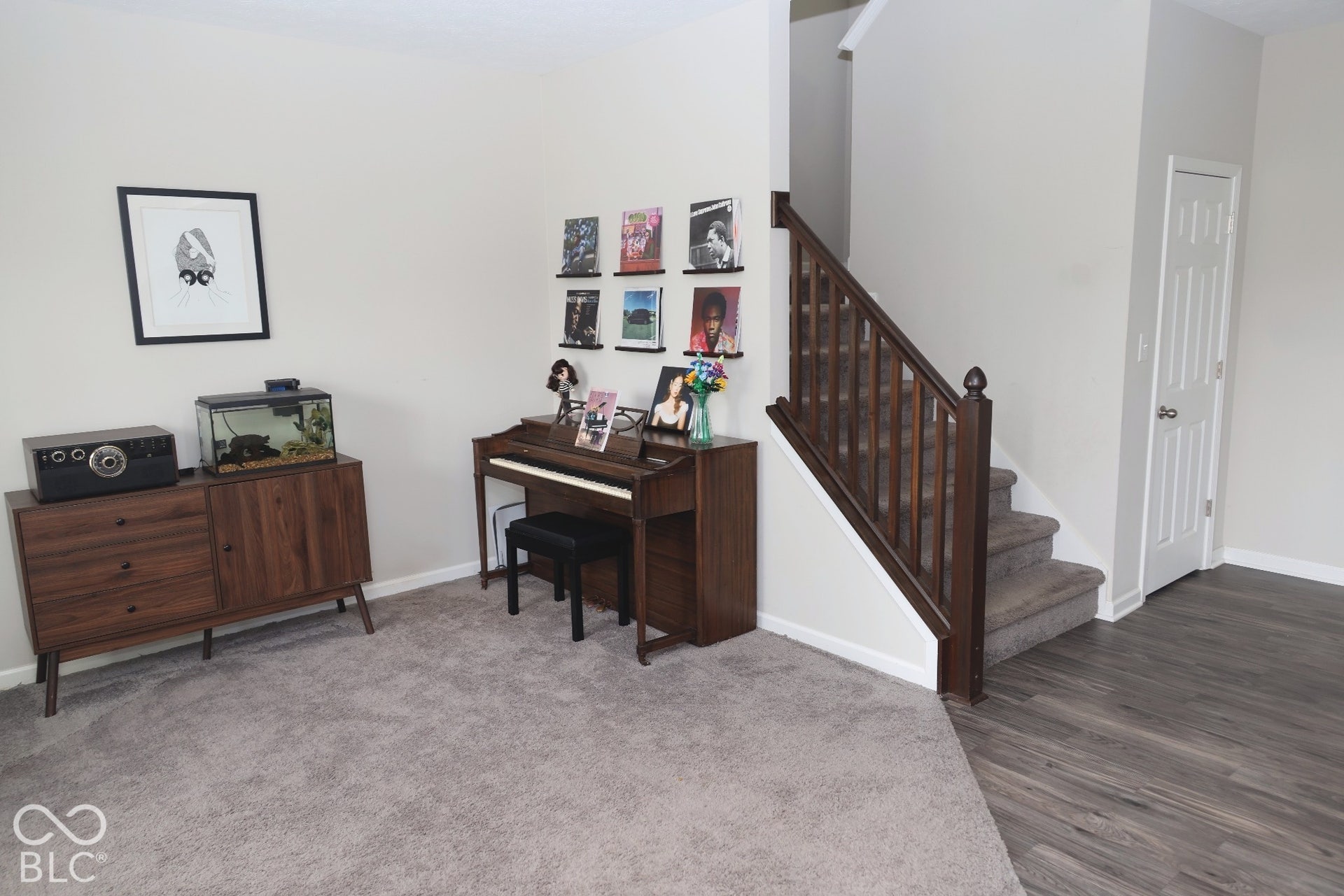 Interior featuring a staircase with a dark wood-finish balustrade, wood-finish flooring, carpeted flooring, and a six-panel door