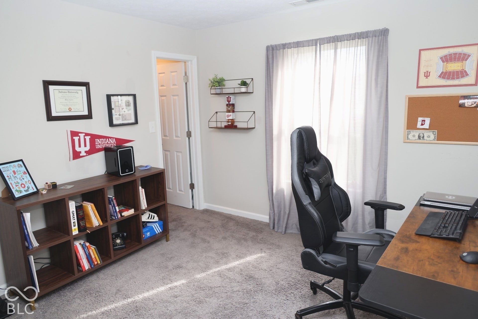 Neutral-toned interior space featuring wall-to-wall carpeting, a single-panel interior door, and wall-mounted metal shelving
