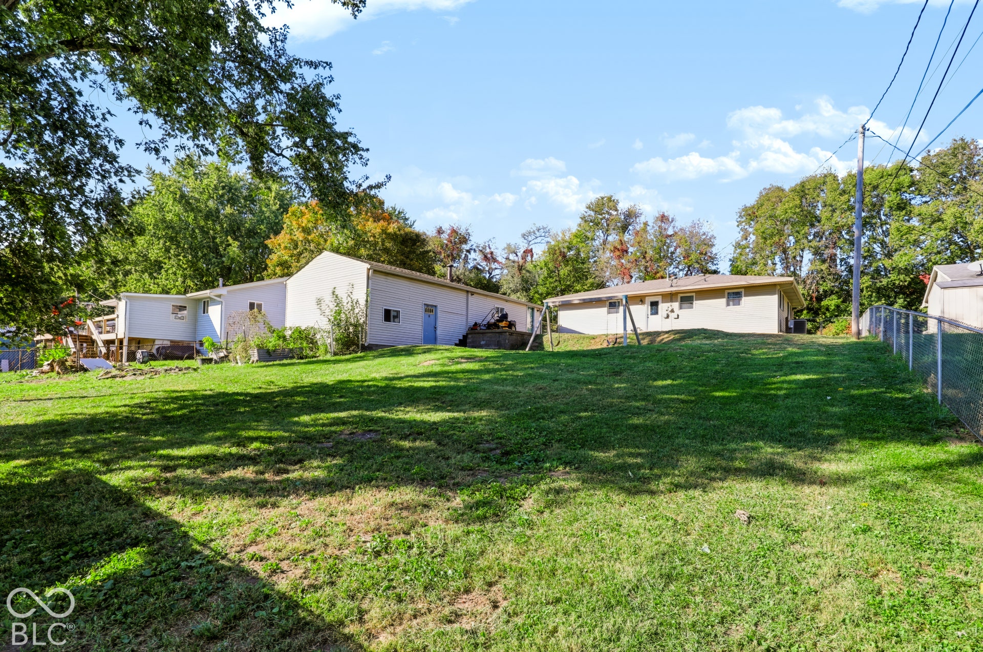 Expansive lawn with mature trees and perimeter chain-link fencing