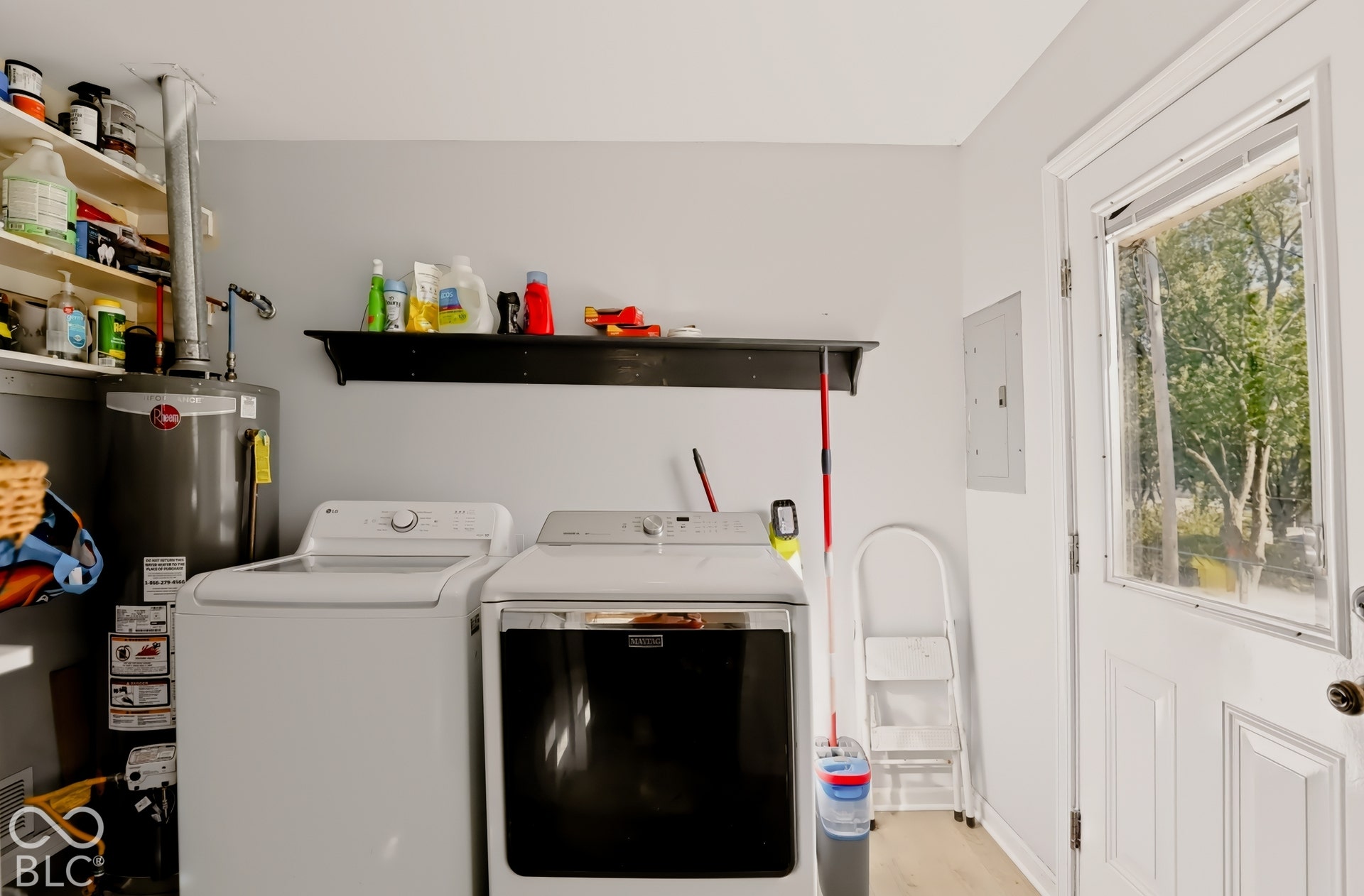 Utility area featuring a wall-mounted shelf, built-in water heater, and a white exterior door with an inset window