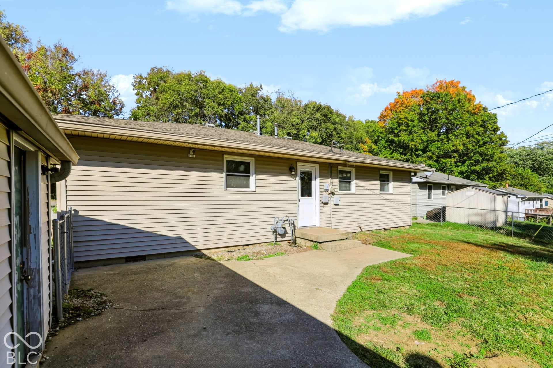 Exterior featuring beige horizontal siding, a concrete patio, and a chain-link fenced yard