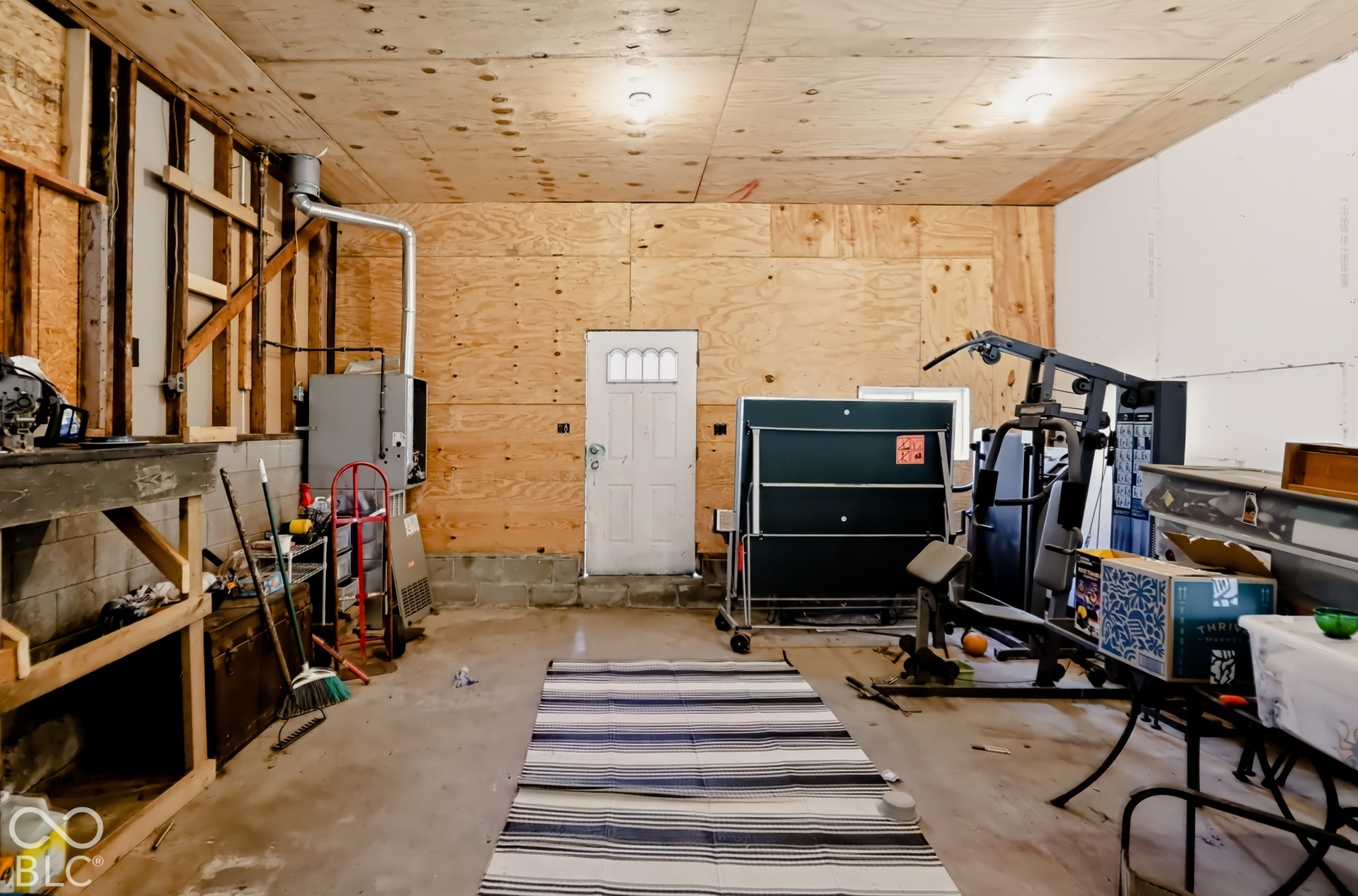 Garage space featuring exposed wood-paneled walls and ceiling, concrete flooring, built-in shelving unit, and a metal exterior door with window inserts