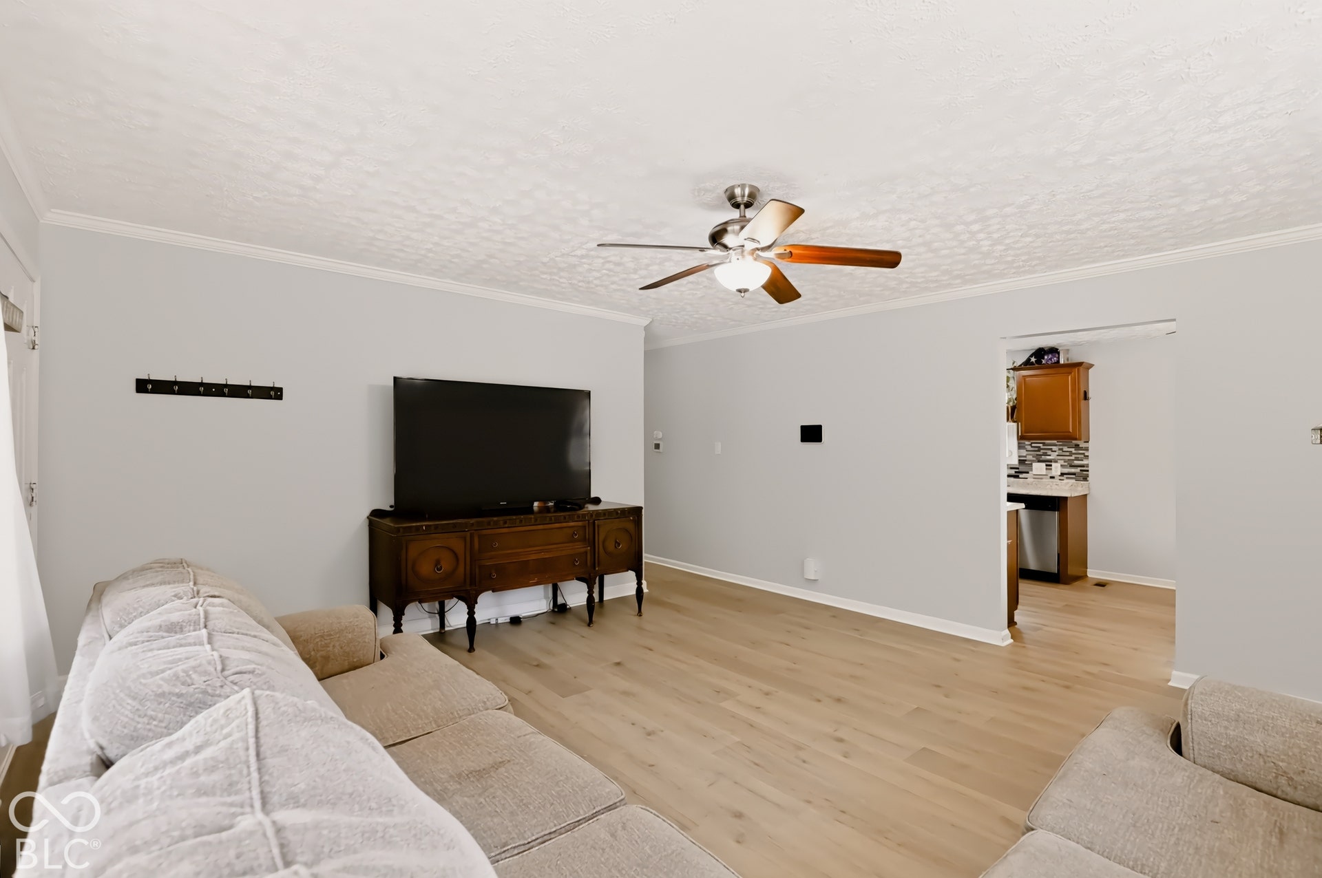 Wood-finish flooring, textured ceiling, and a central ceiling fan with integrated lighting