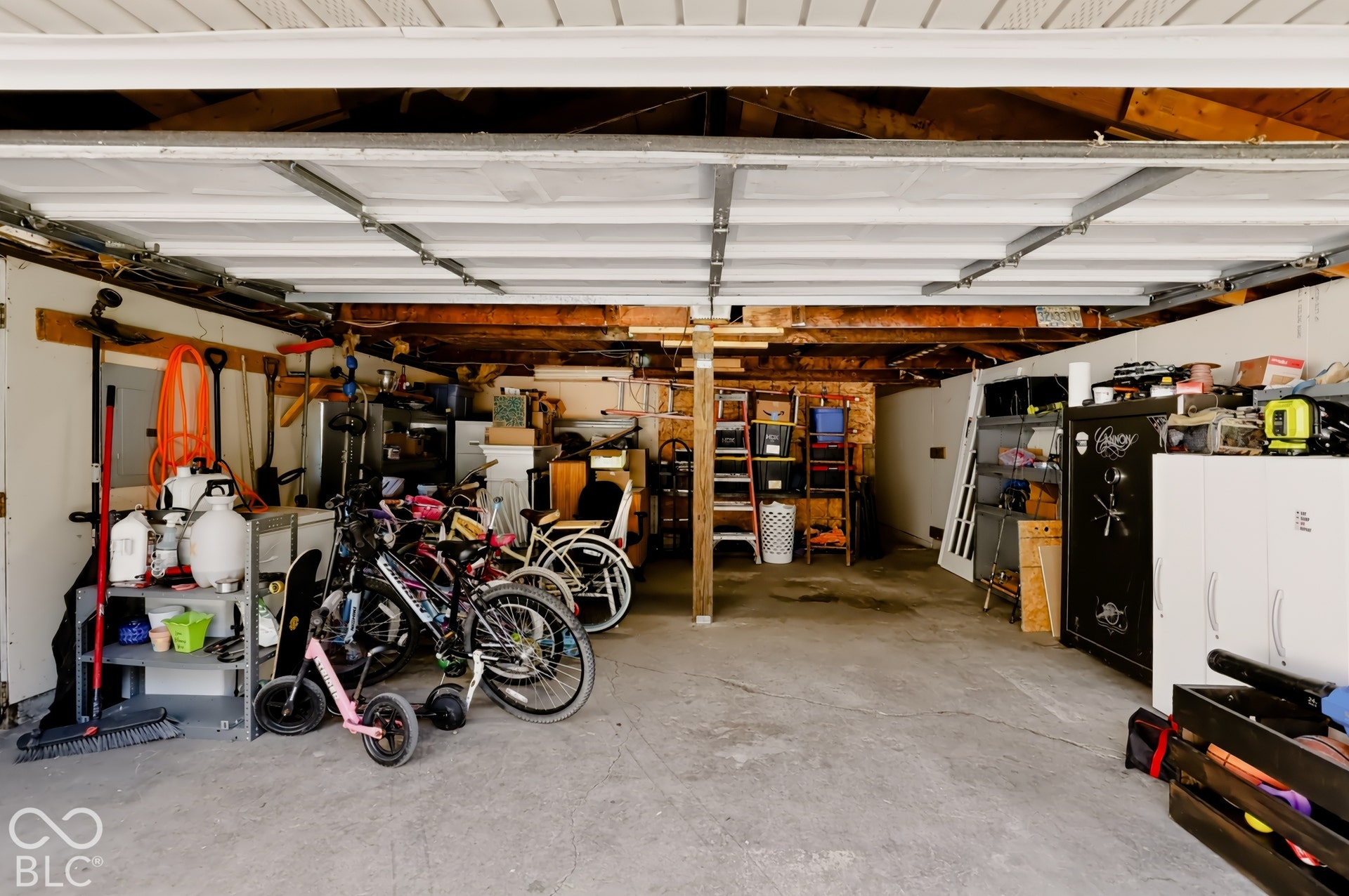 Two-car garage featuring a concrete floor, sectional overhead door, and exposed wood ceiling joists