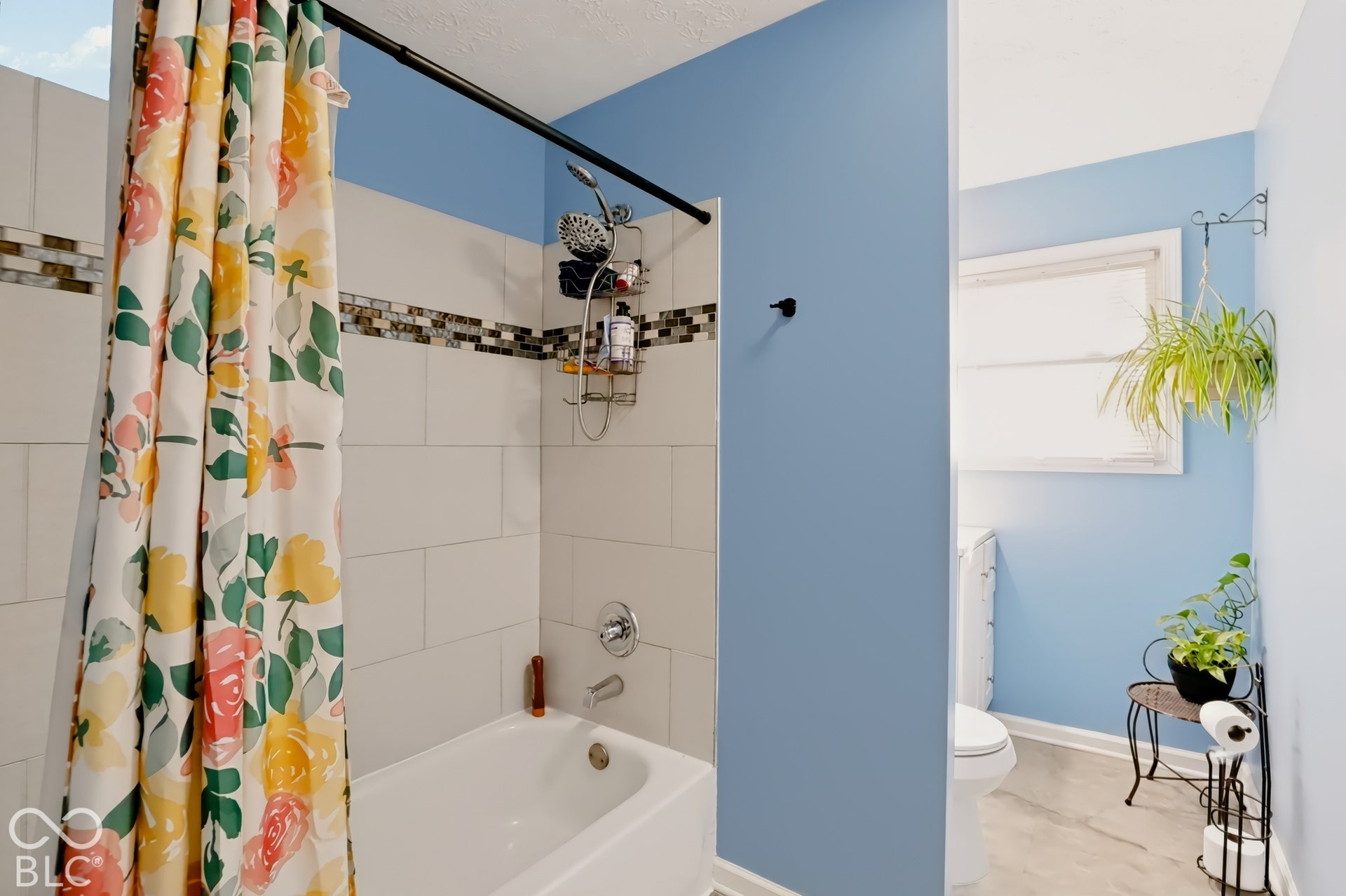 Full bathroom featuring a tub-shower combination with light-toned wall tile, a decorative horizontal glass mosaic accent border, and chrome plumbing fixtures