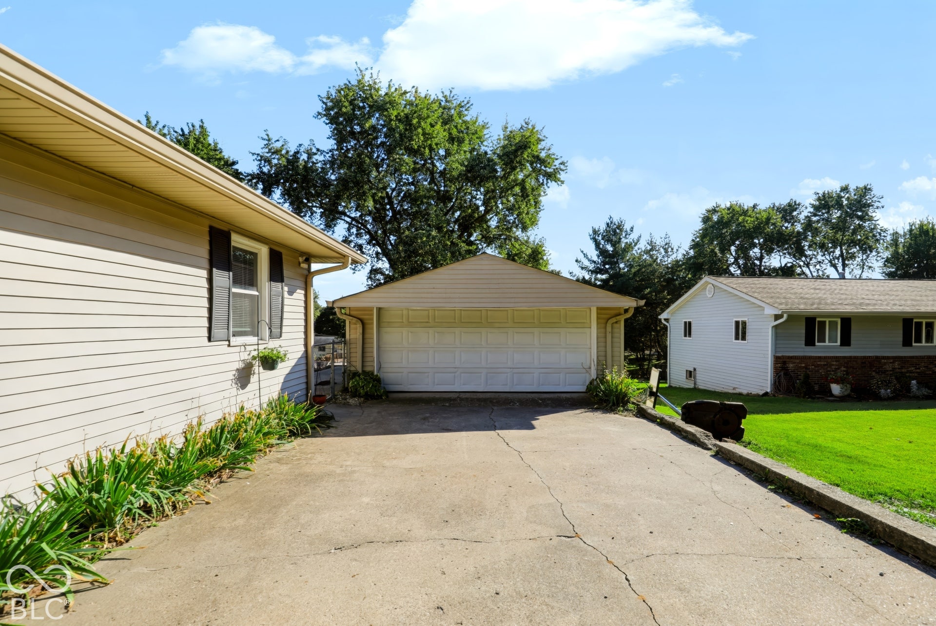 Concrete driveway leading to a detached garage featuring horizontal siding and a sectional garage door