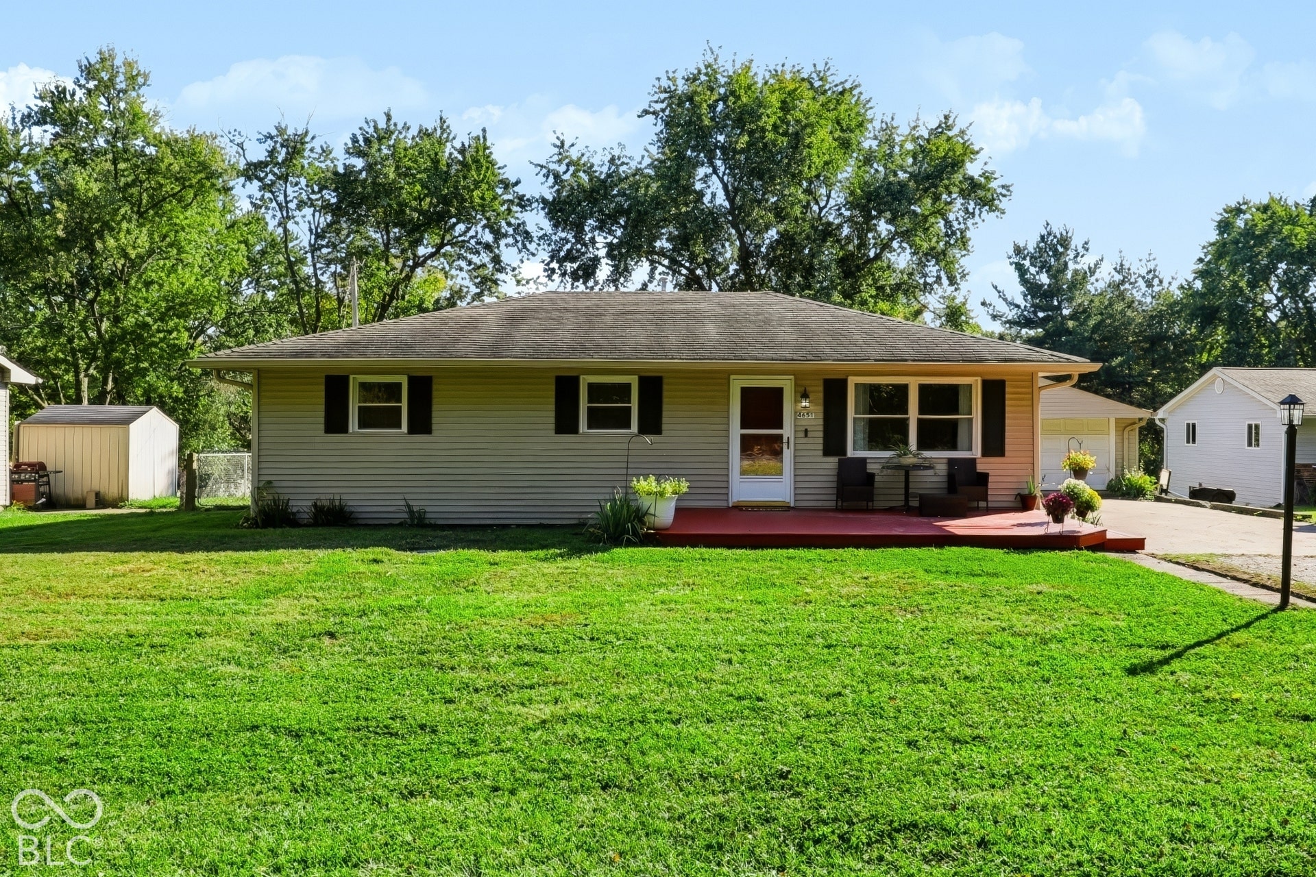 Single-story residence featuring horizontal siding, a hipped roof, a raised wooden deck, and mature landscaping