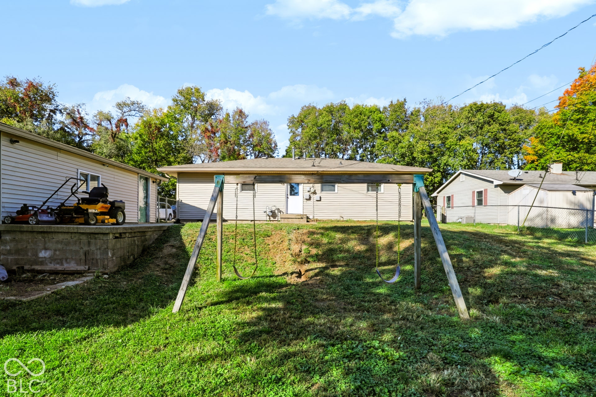 Backyard featuring a grass lawn, chain-link fencing, and mature trees