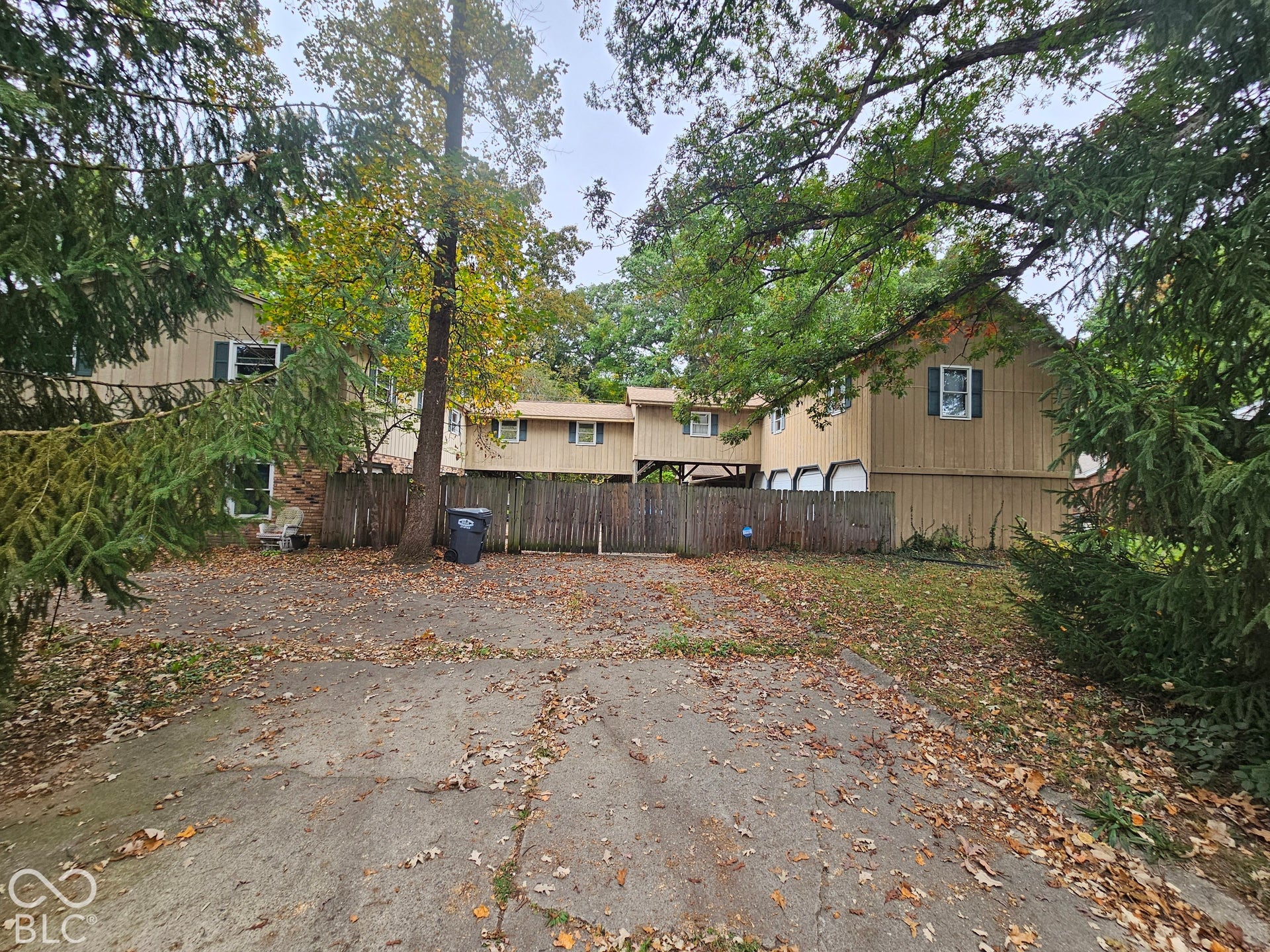 Multi-level exterior featuring wood siding, a paved driveway, and a wooden privacy fence