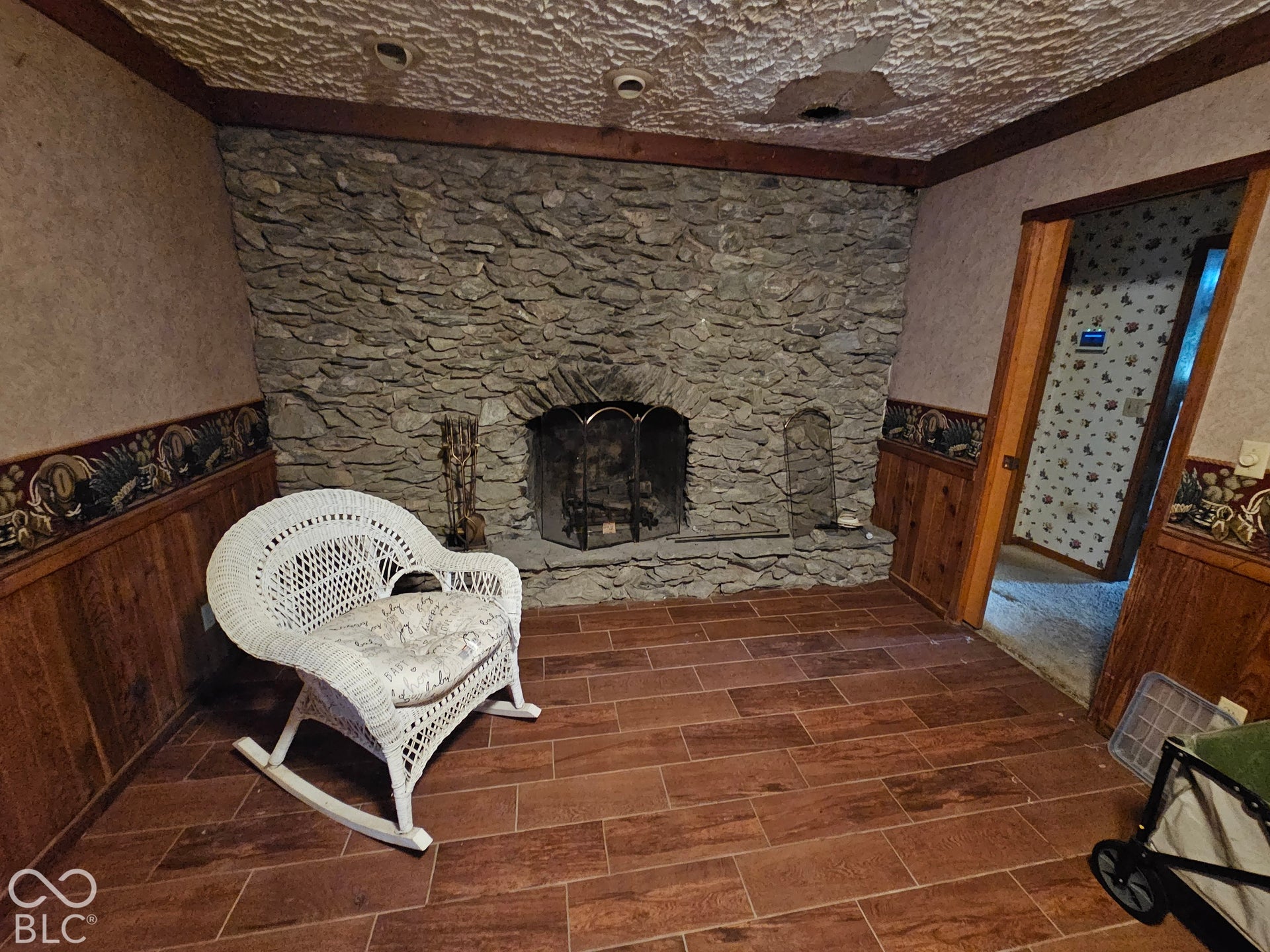Floor-to-ceiling natural stone fireplace with arched firebox, hearth, and wood-finish tile flooring
