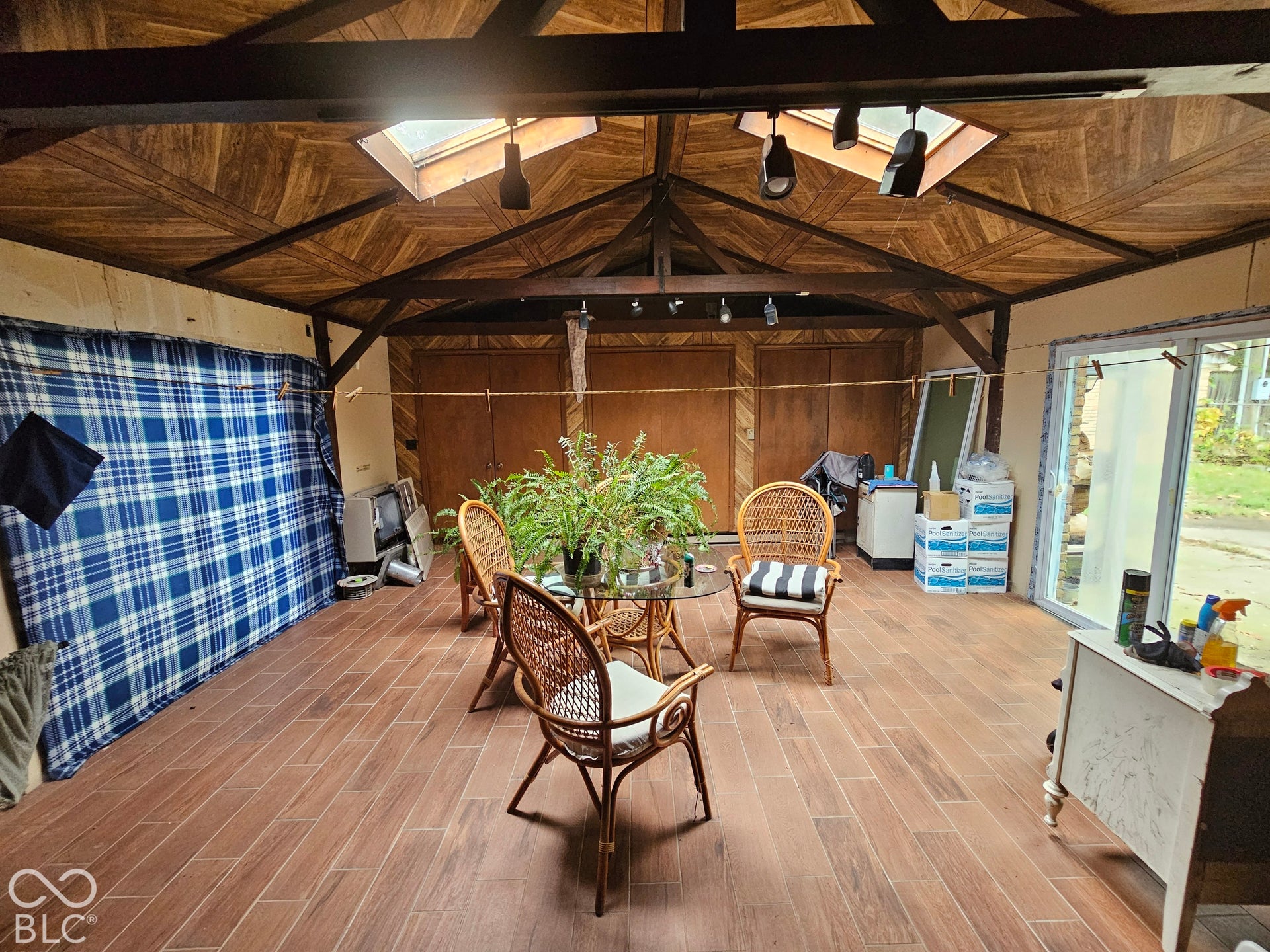 Vaulted ceiling featuring herringbone wood detailing, exposed trusses, multiple skylights, and wood-finish flooring